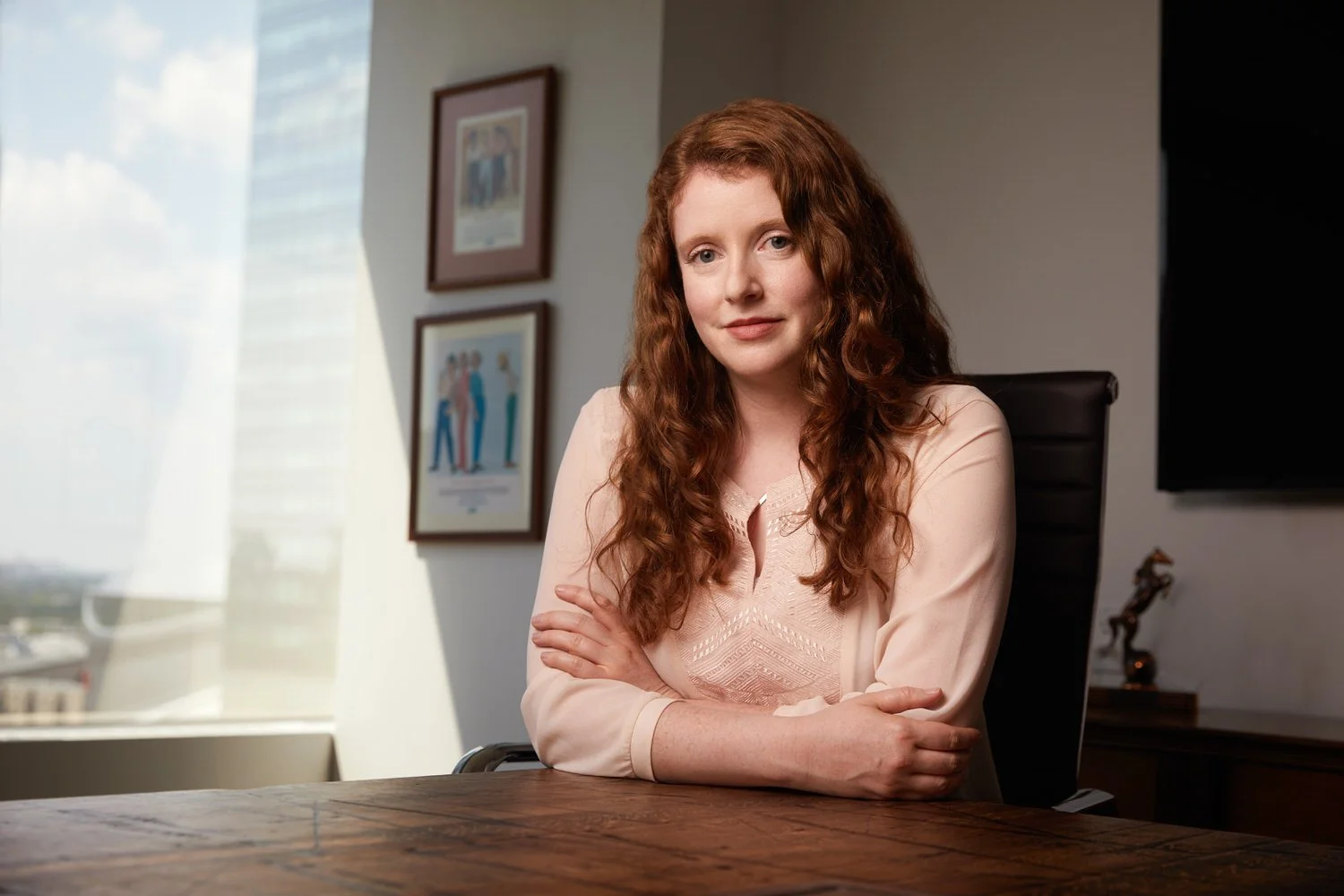 Office portrait at a wooden desk, arms folded