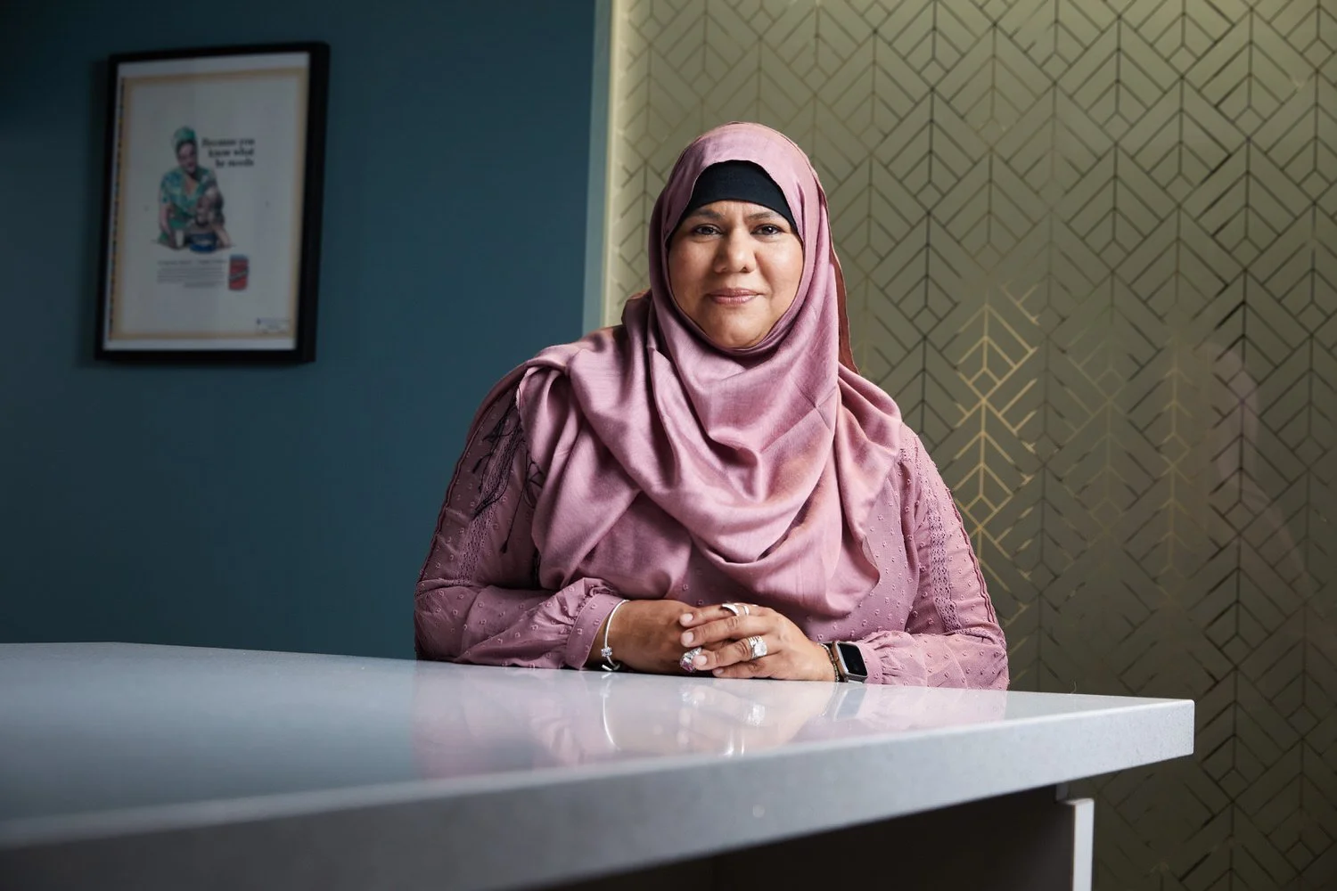 Office portrait at a white counter, pink hijab