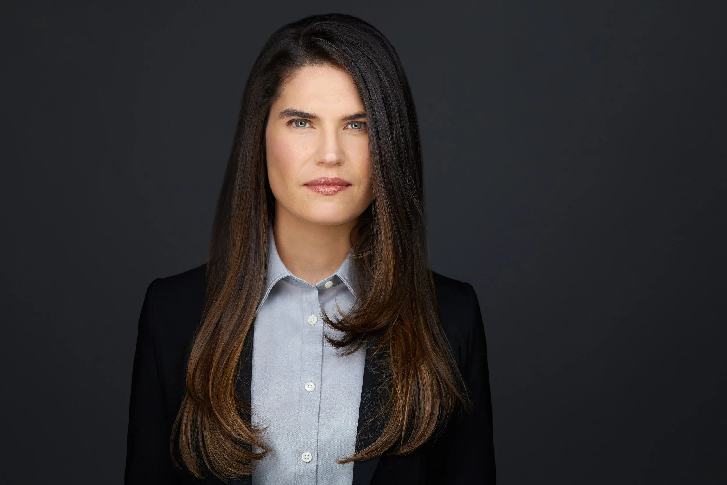A corporate headshot on grey, framed so the face stays inside the circle the platform crops to