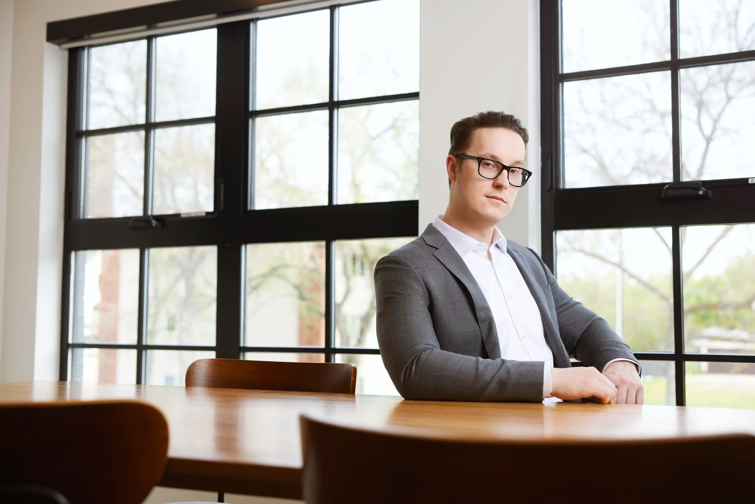 Office portrait at a table by the windows, glasses