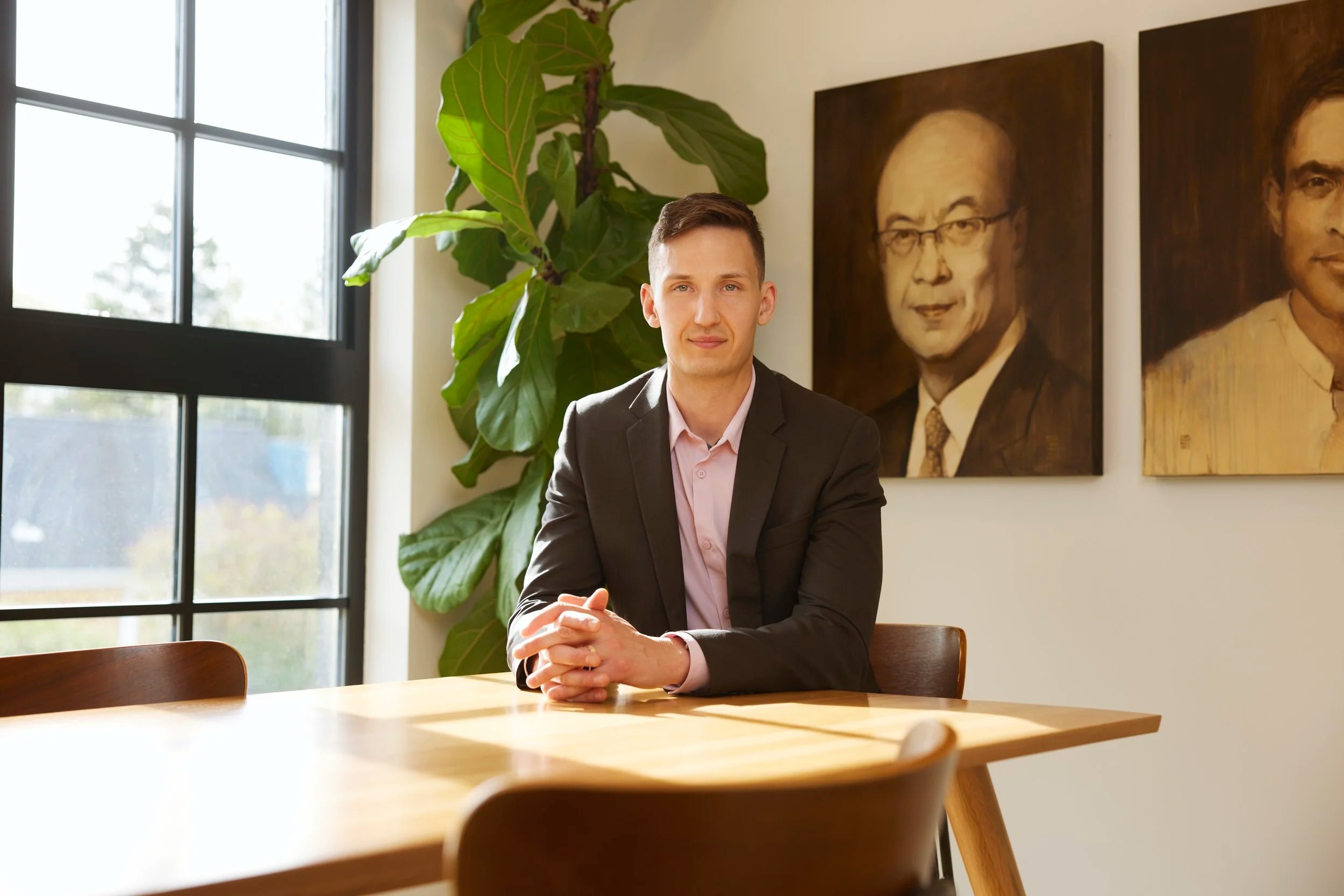 Office portrait at a table under two painted portraits