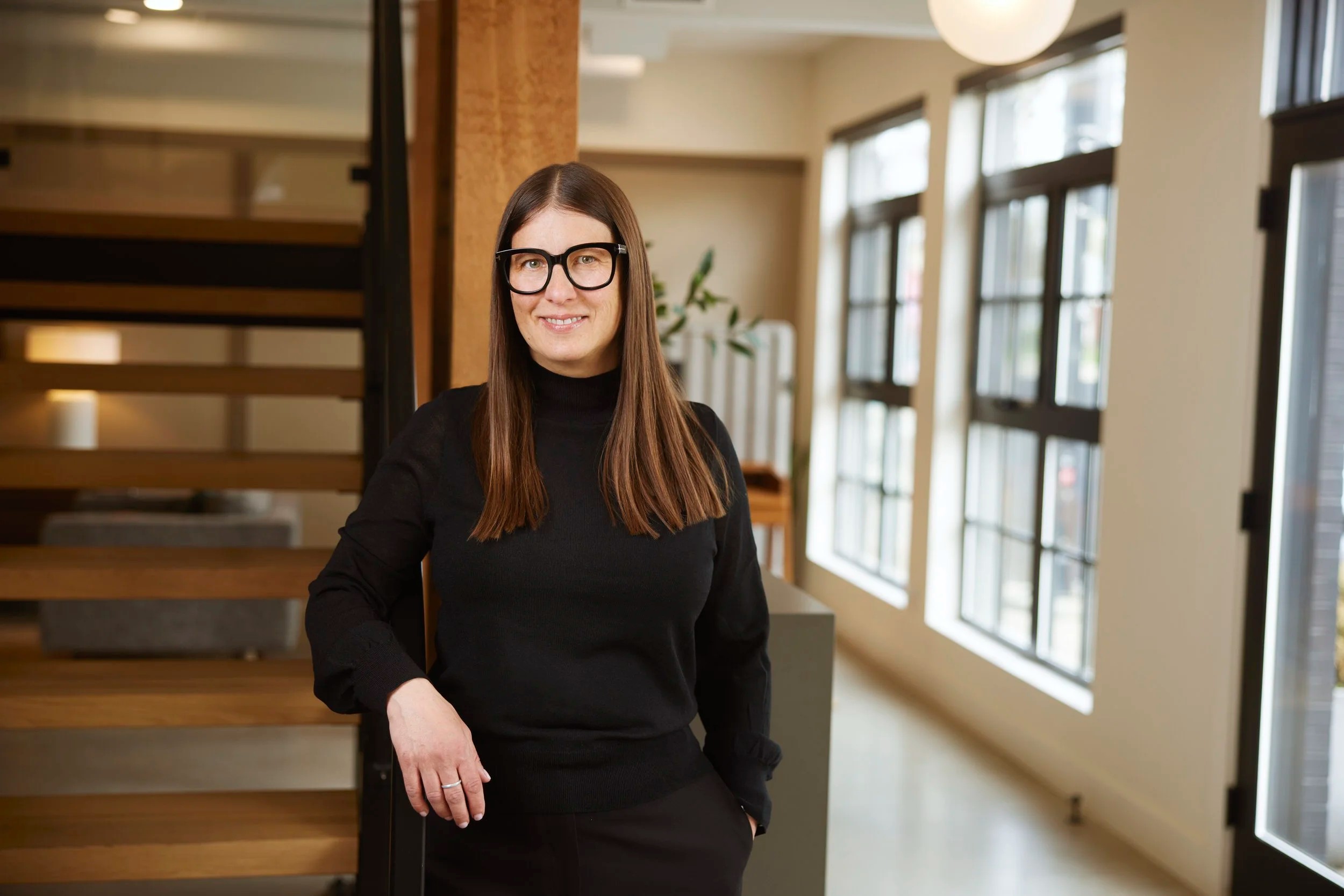 Office portrait by the stairs, black sweater