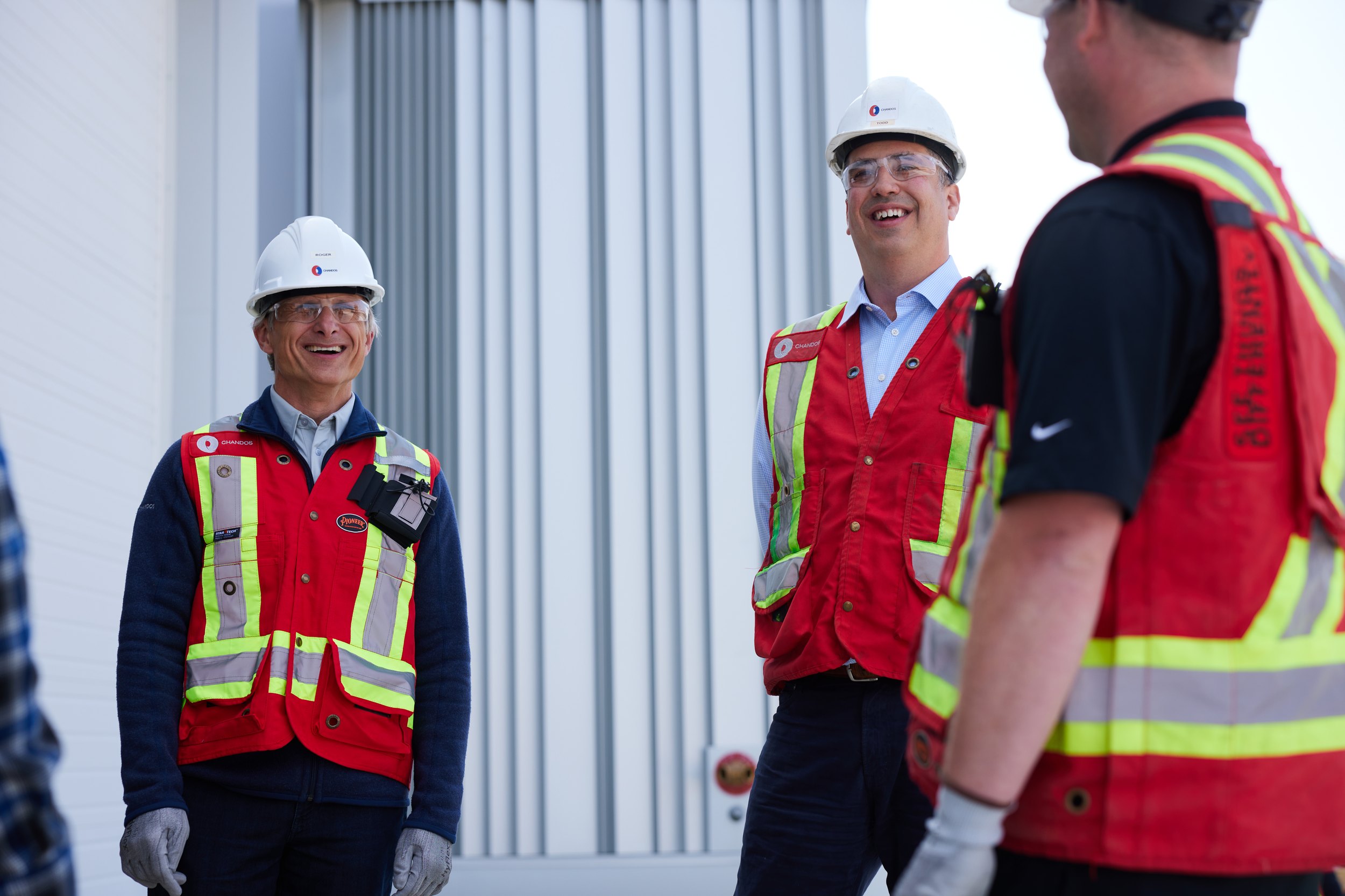 Three people talking beside new metal cladding