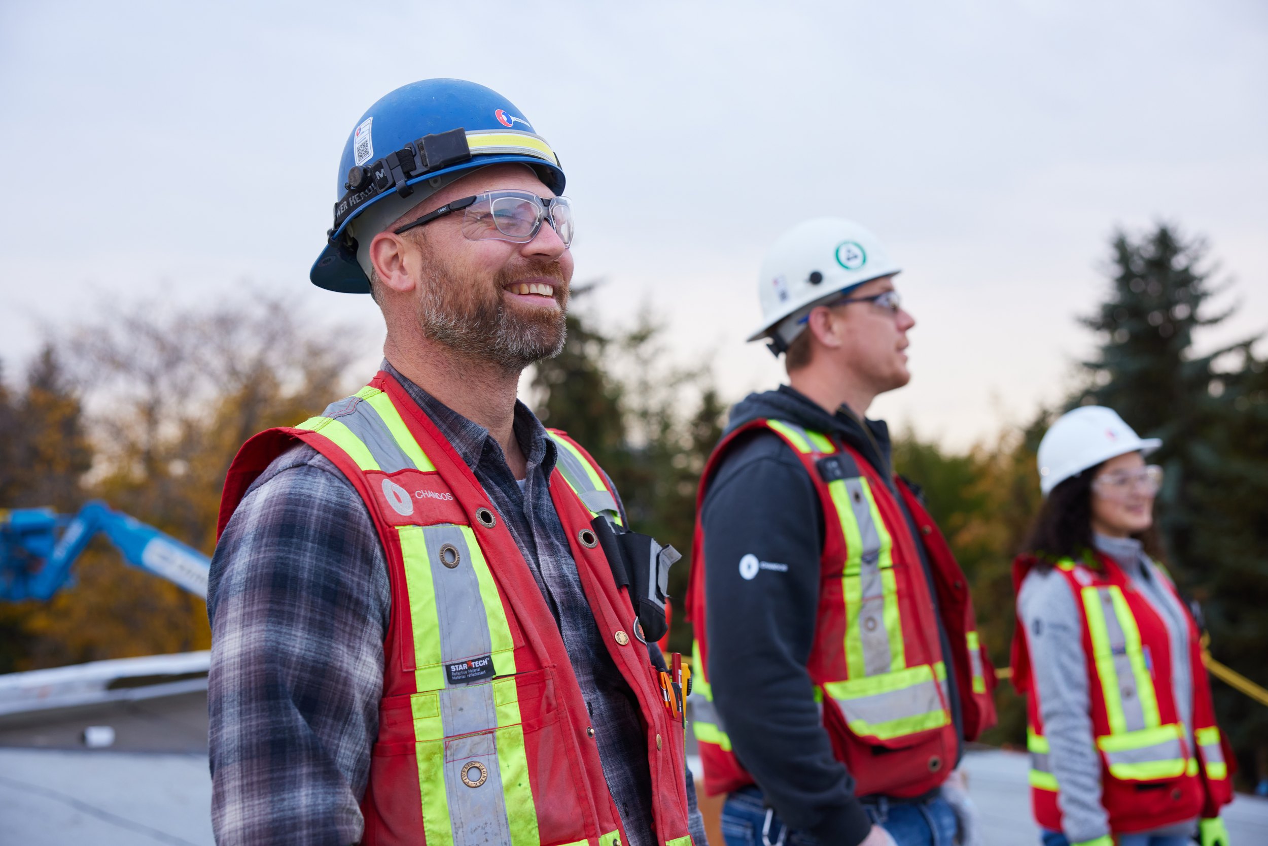 Three of the crew outside in hard hats, one of them laughing