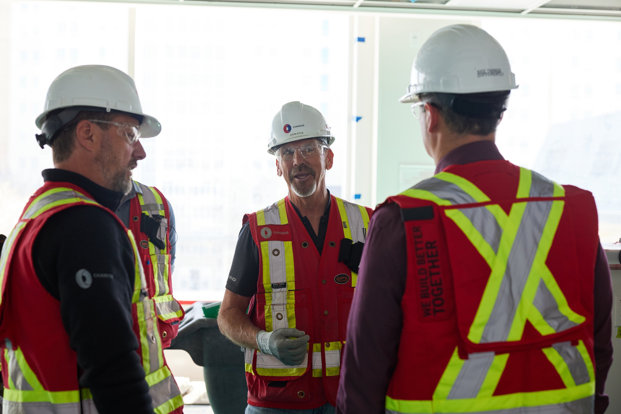Three men in hard hats talking in an unfinished interior