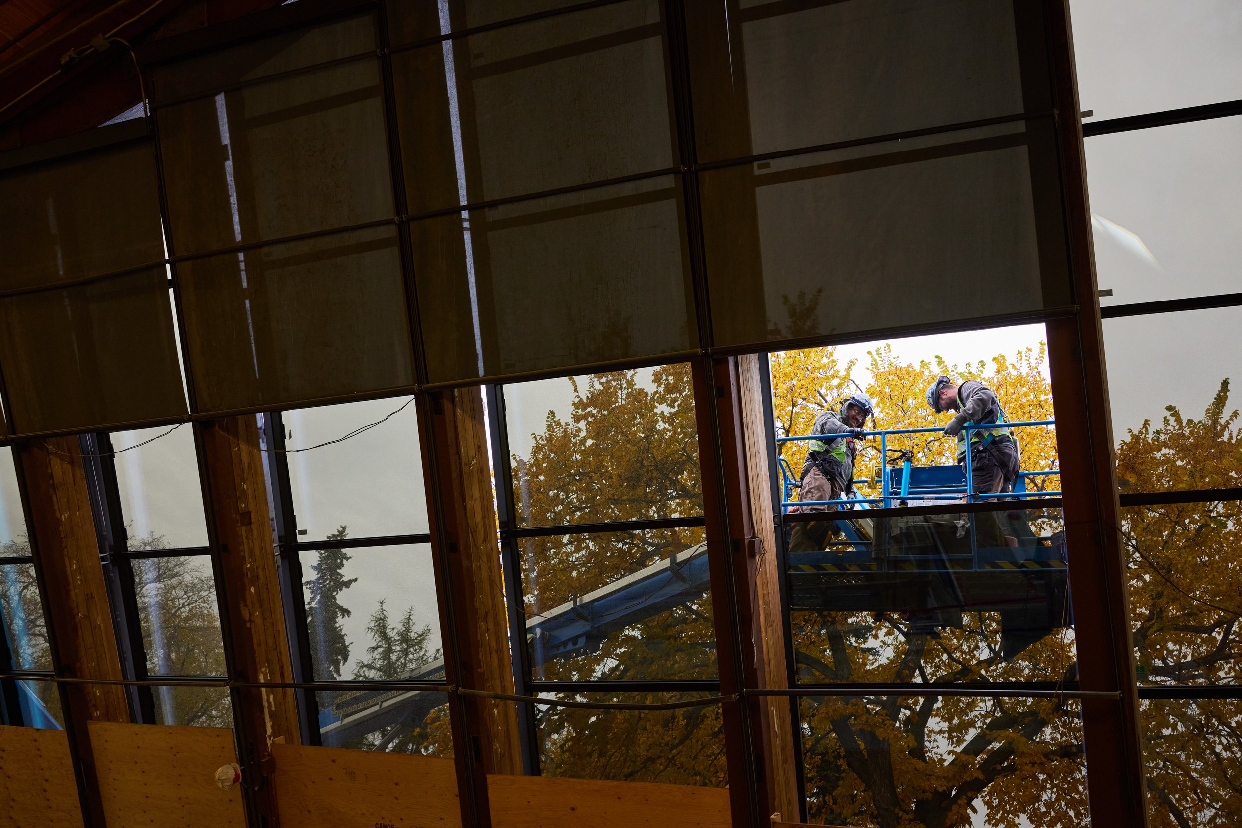 Two workers on a lift, seen through a window frame