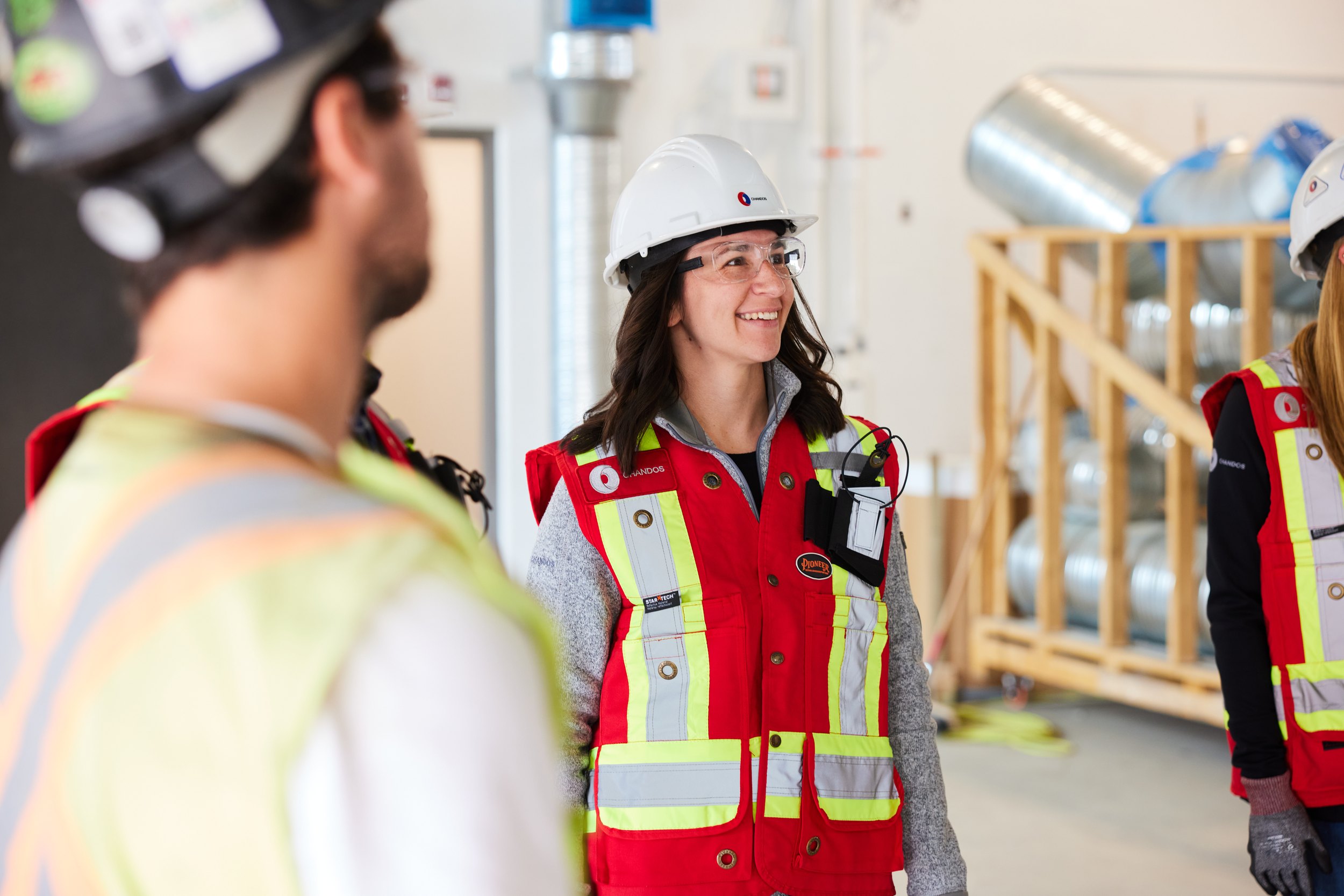 A woman laughing among the crew, ductwork behind her