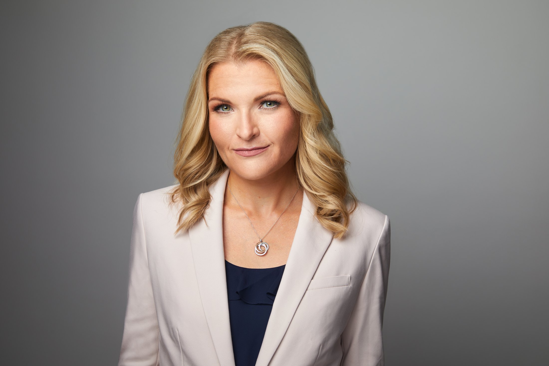 A studio portrait of the same broadcaster in black, against grey