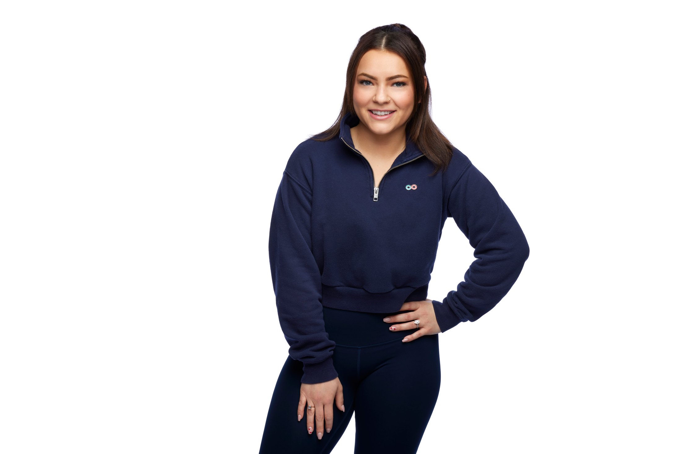 A woman in a navy quarter-zip, hands at her waist