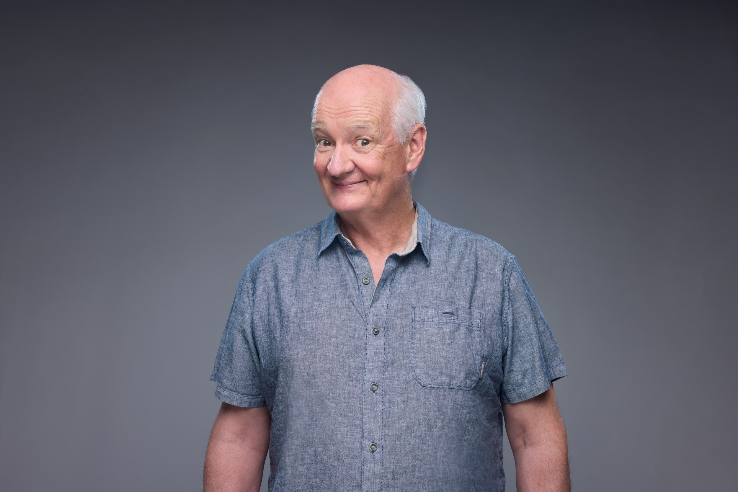 The blue shirt, his head tilted, a sly smile