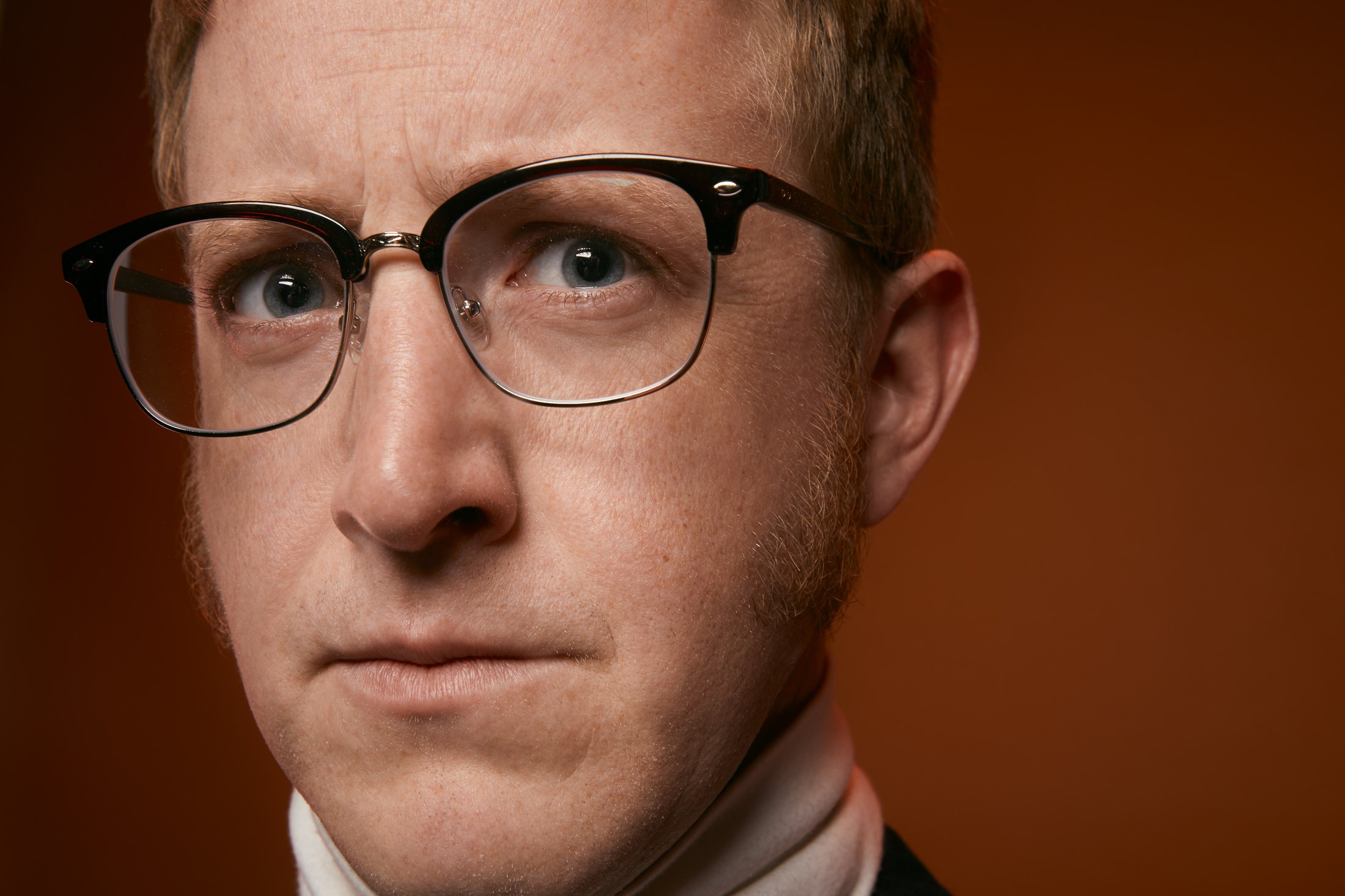 A man in heavy black glasses, close in against rust