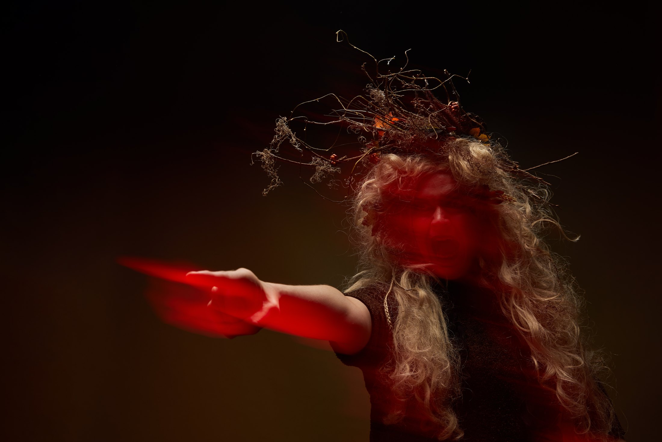 Macbeth promo, a multiple exposure in red light: a hand thrust toward the camera, the face trailing behind it