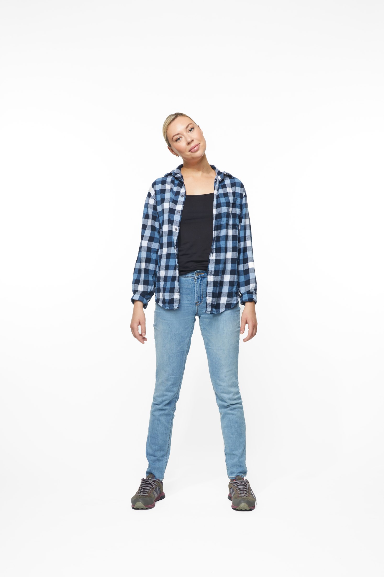 A woman in a plaid shirt and jeans in one of the program’s stretches, full length on white
