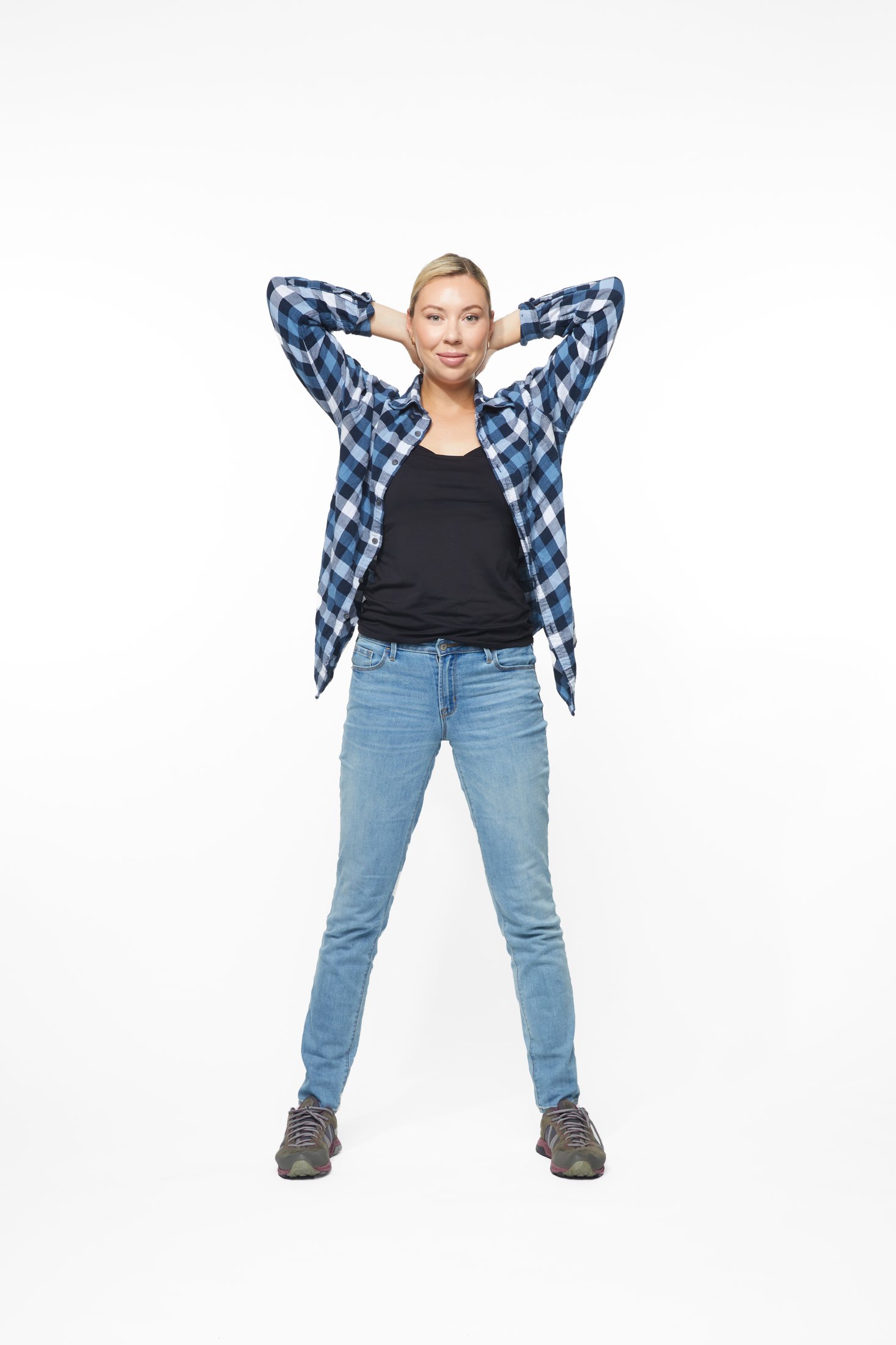 A woman in a plaid shirt and jeans in one of the program’s stretches, full length on white