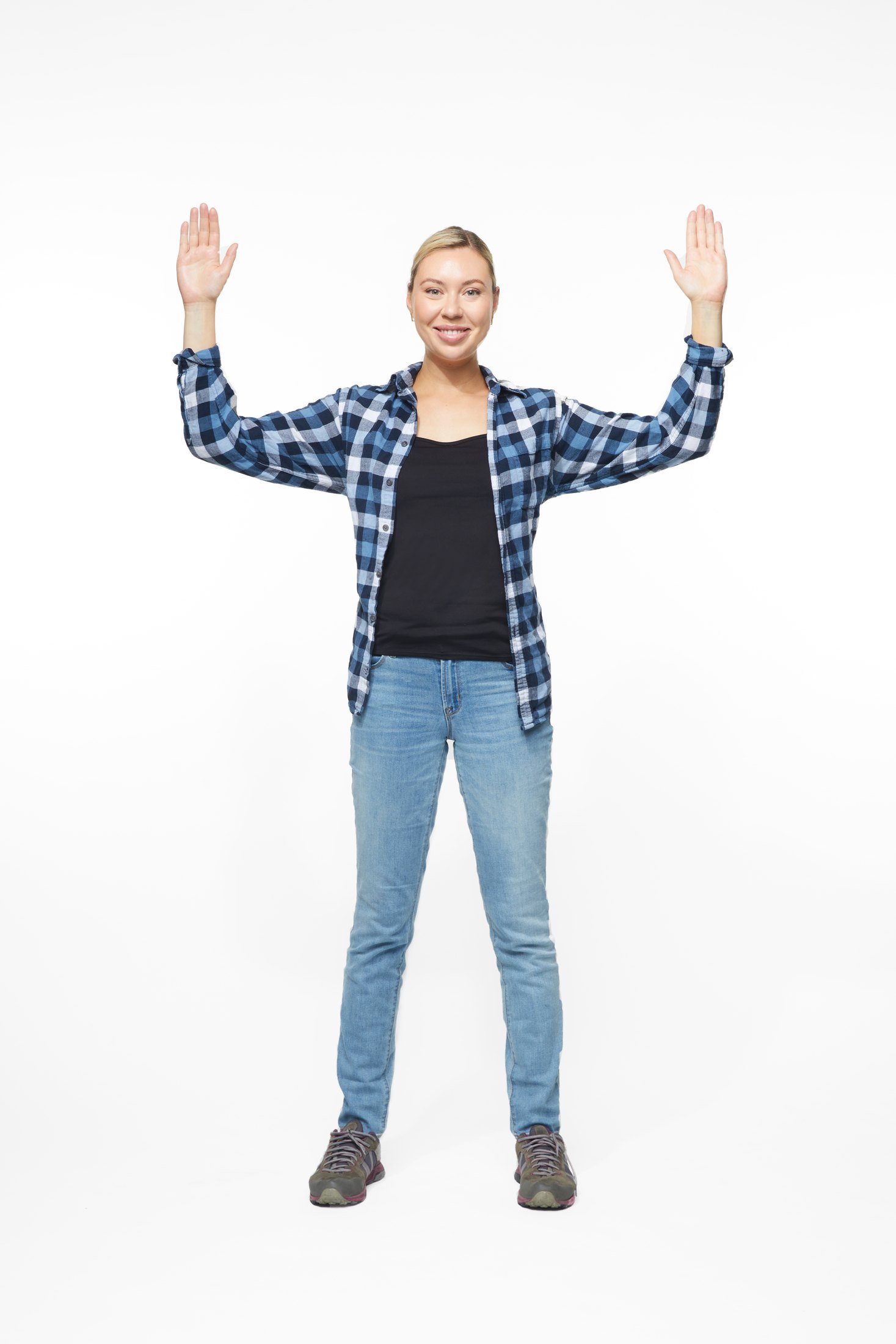 A woman in a plaid shirt and jeans in one of the program’s stretches, full length on white