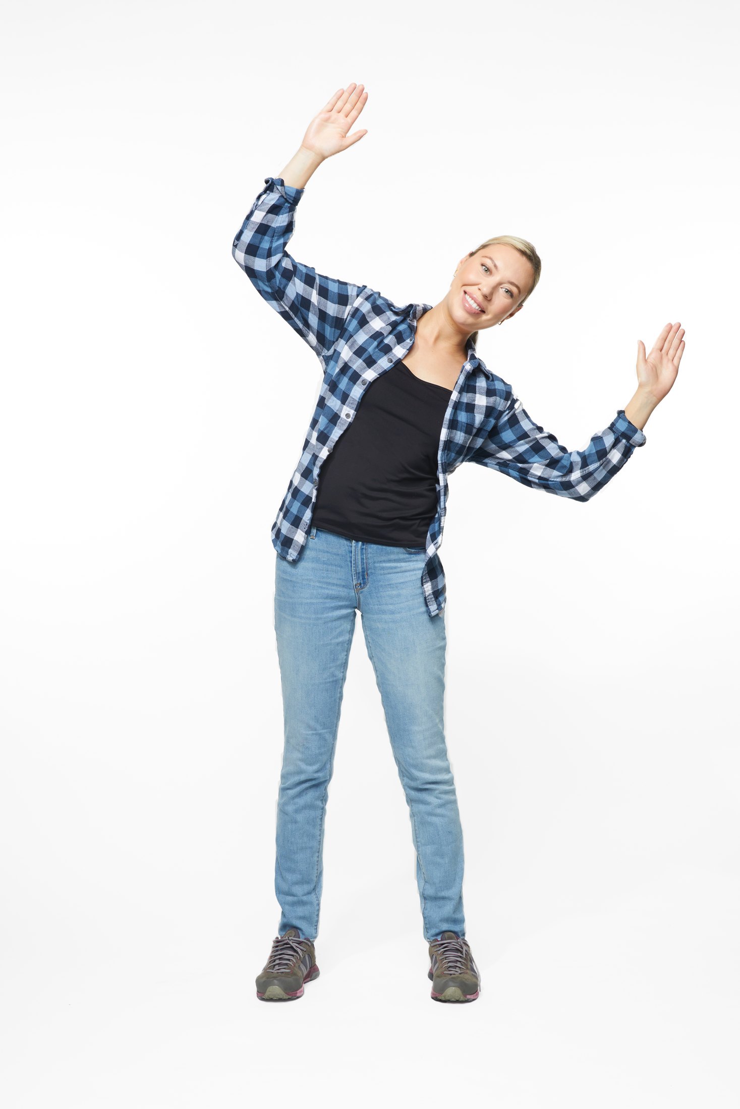 A woman in a plaid shirt and jeans in one of the program’s stretches, full length on white