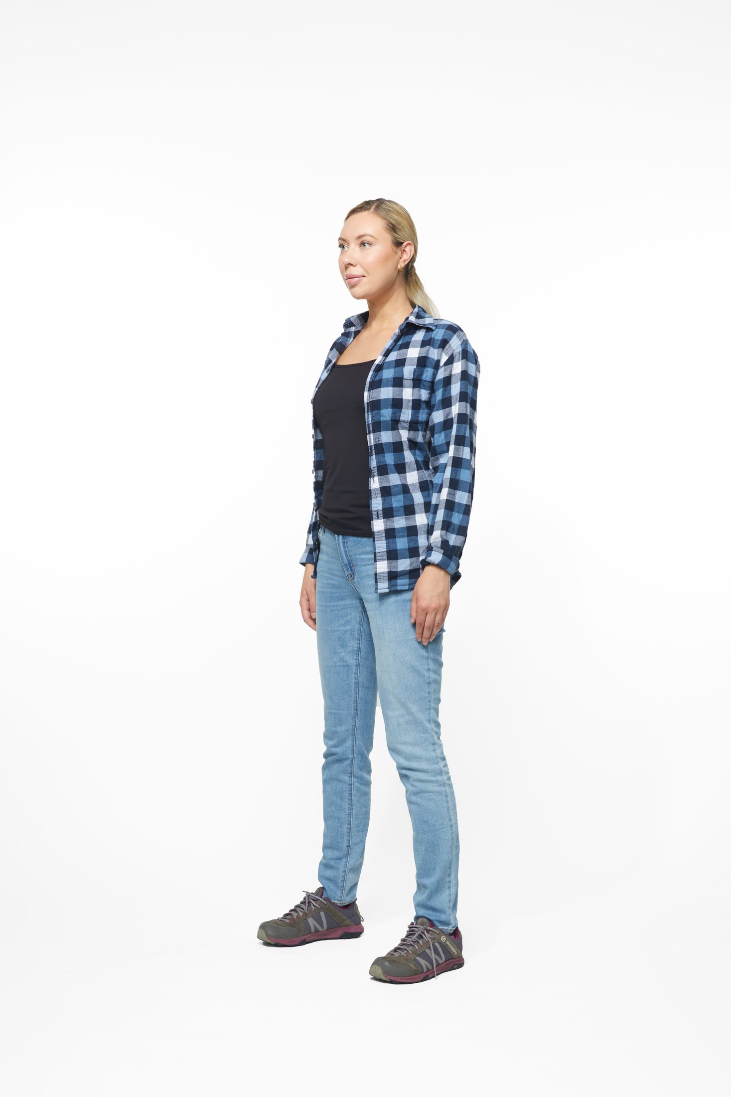 A woman in a plaid shirt and jeans in one of the program’s stretches, full length on white