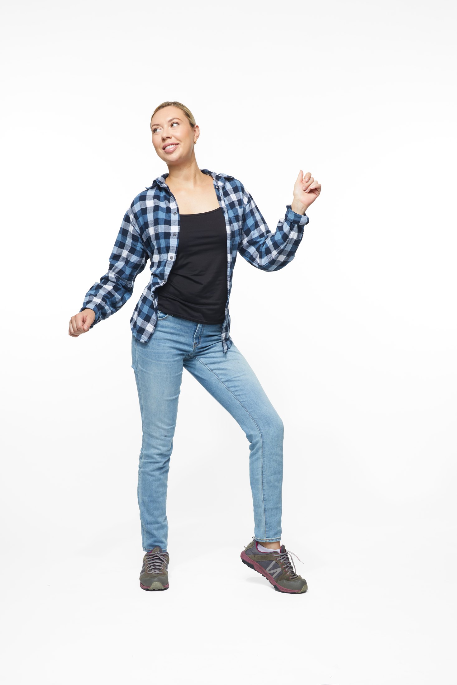 A woman in a plaid shirt and jeans in one of the program’s stretches, full length on white