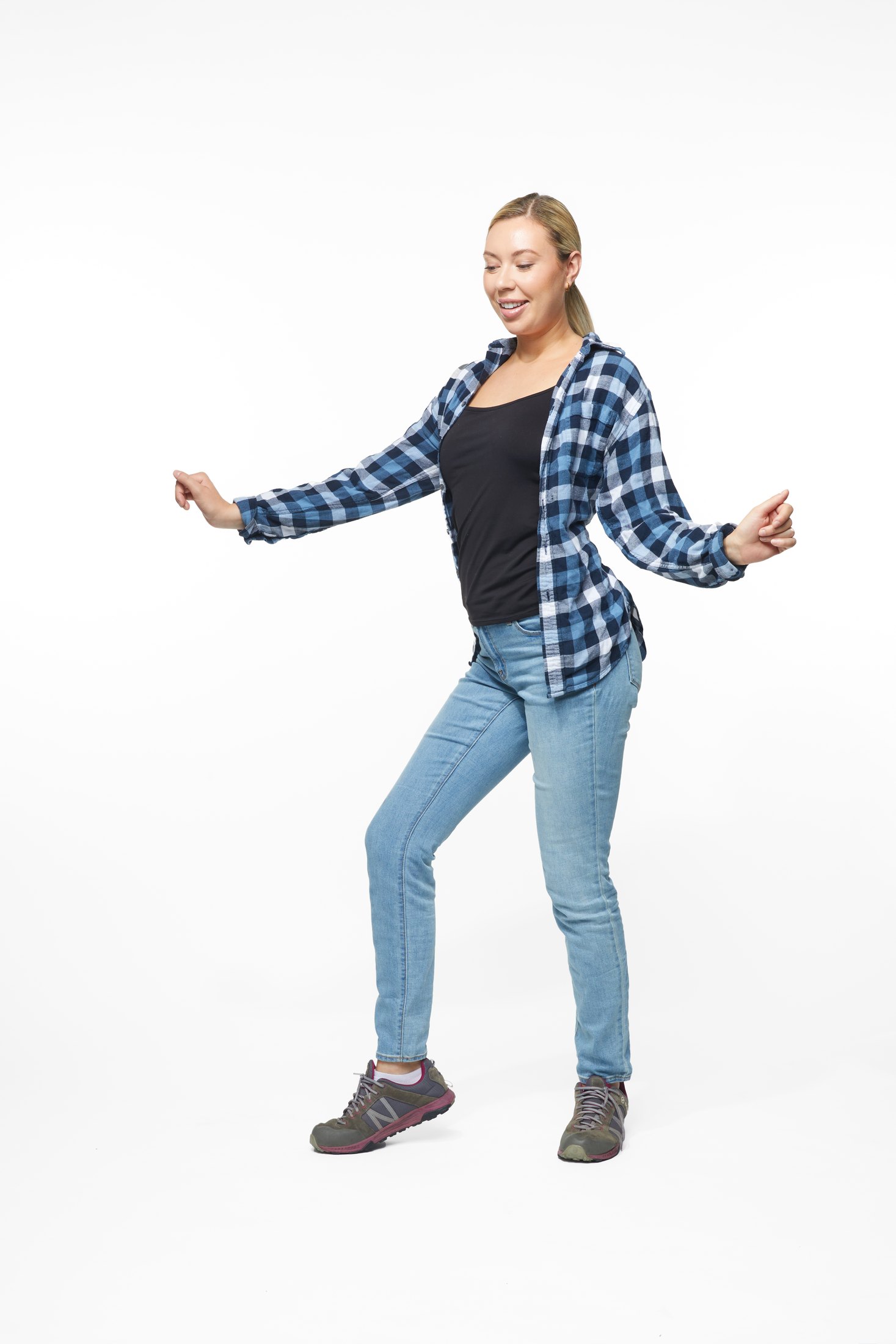 A woman in a plaid shirt and jeans in one of the program’s stretches, full length on white