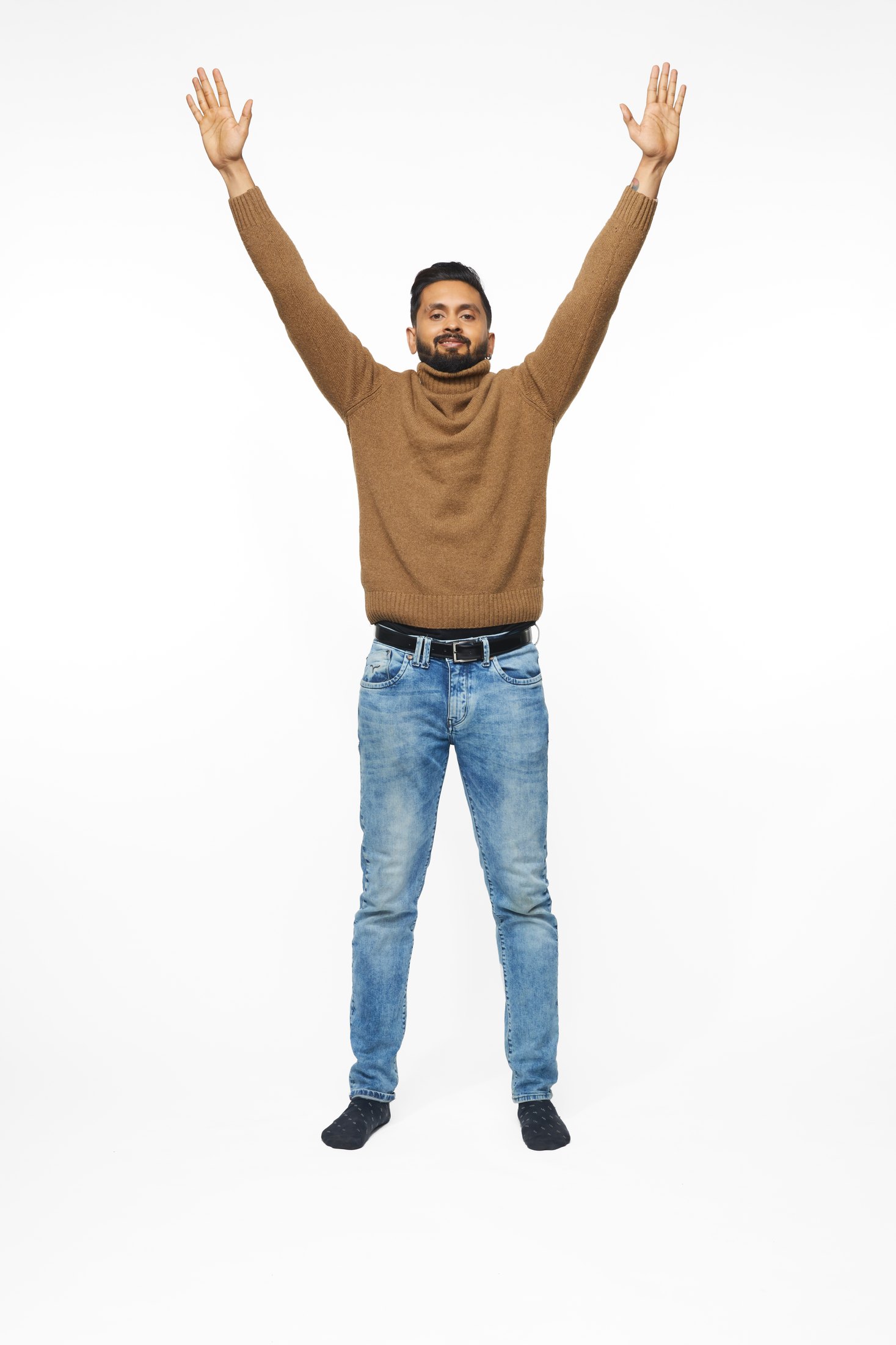 A man in a brown sweater and jeans in one of the program’s stretches, full length on white