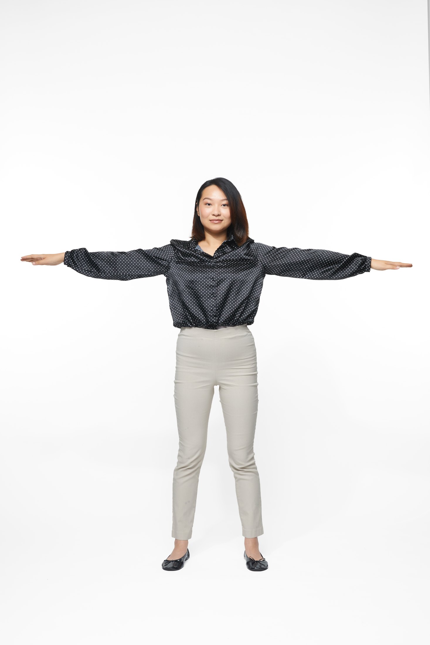 A woman in a black jacket and pale trousers in one of the program’s stretches, full length on white