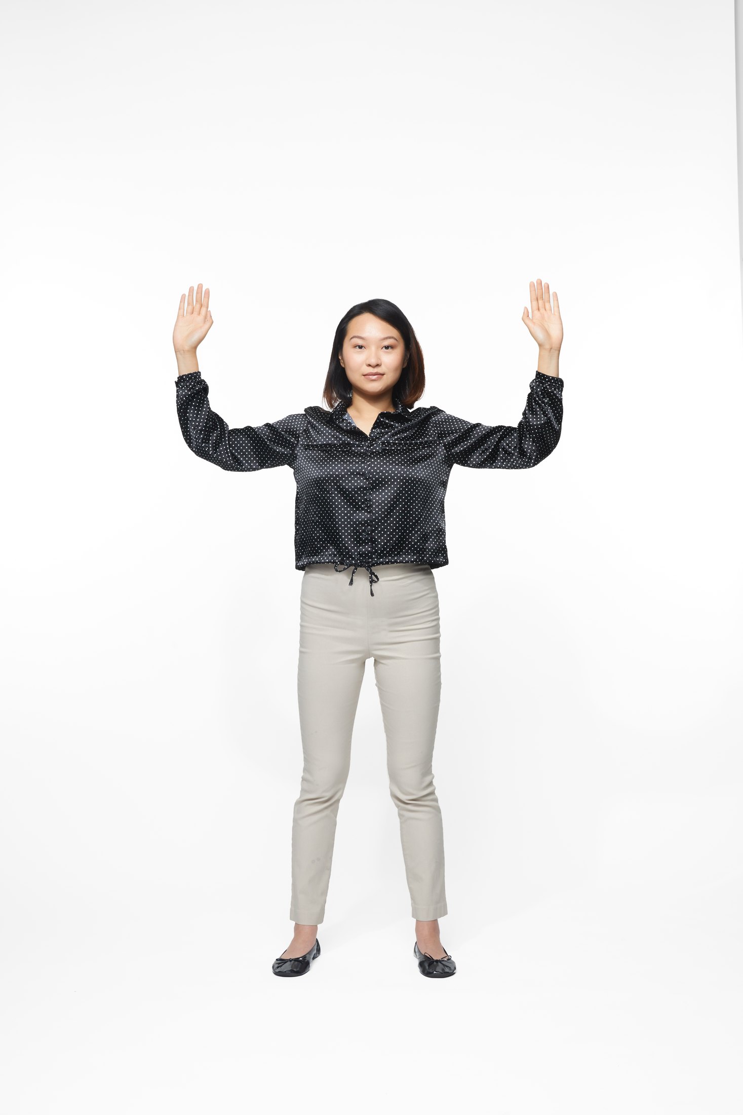A woman in a black jacket and pale trousers in one of the program’s stretches, full length on white