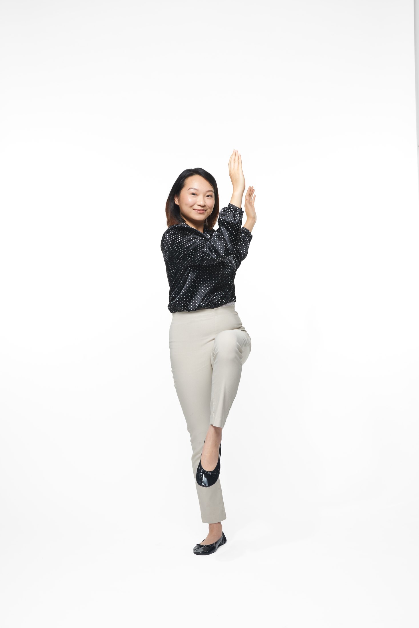 A woman in a black jacket and pale trousers in one of the program’s stretches, full length on white