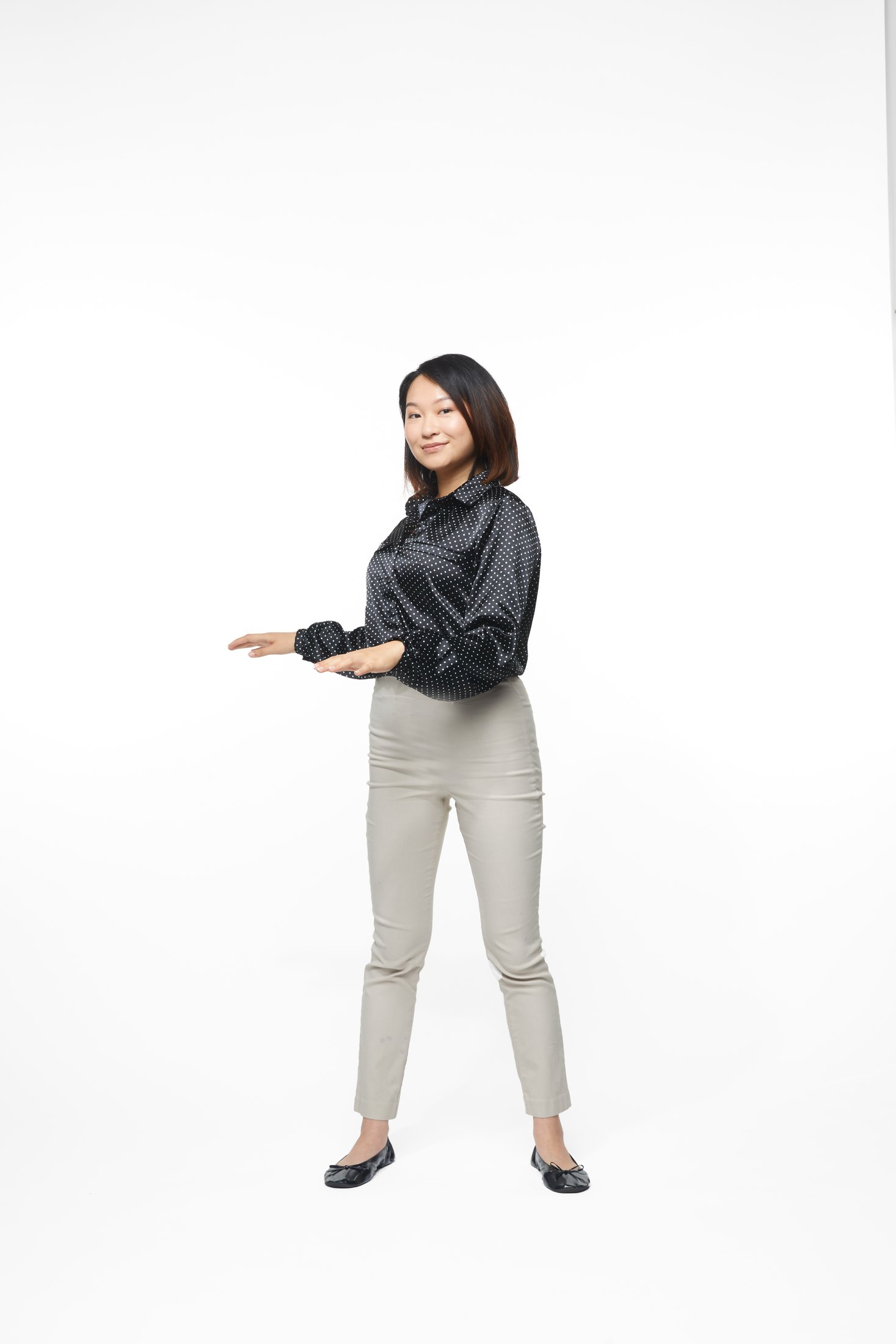A woman in a black jacket and pale trousers in one of the program’s stretches, full length on white