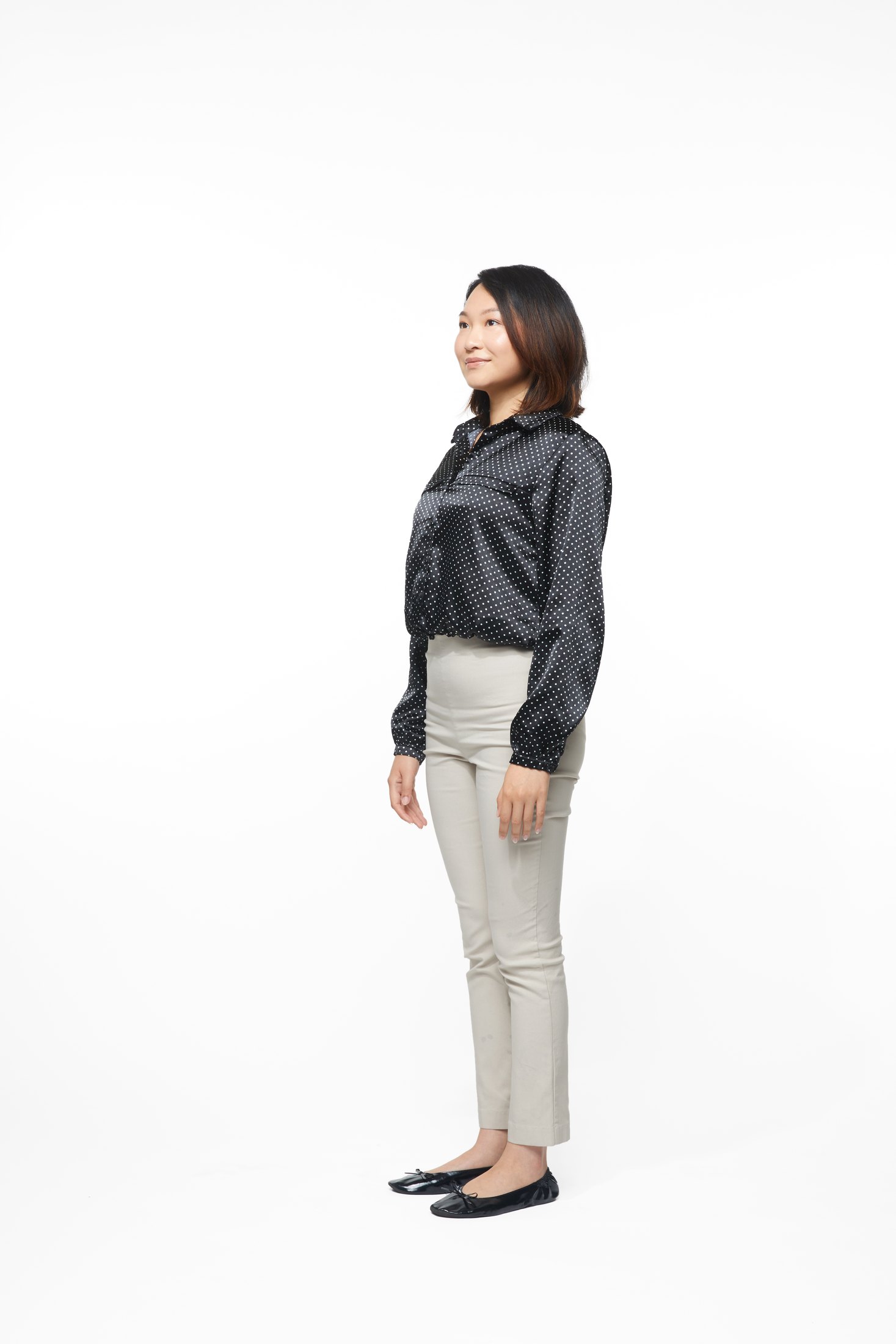 A woman in a black jacket and pale trousers in one of the program’s stretches, full length on white