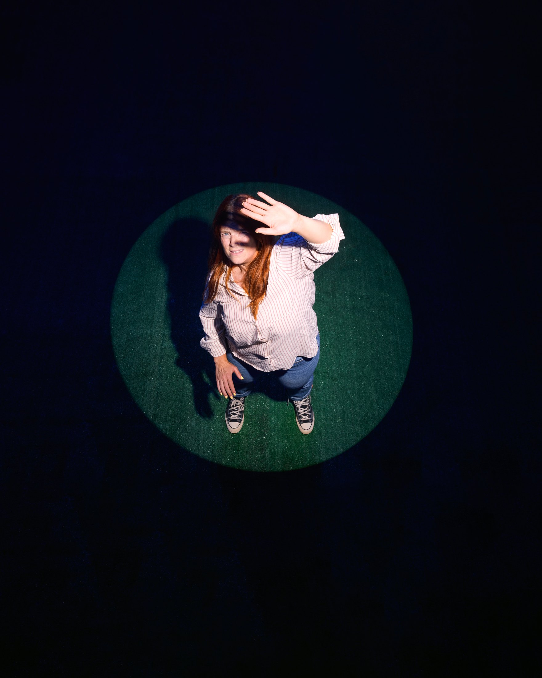 A performer lit in a circle of light against black