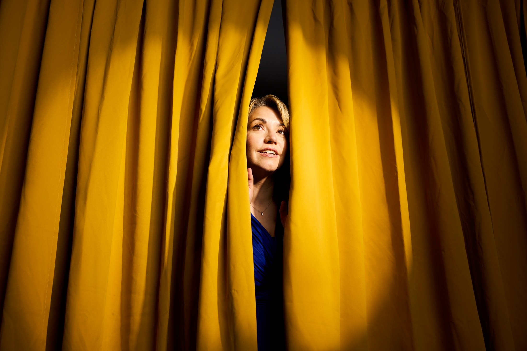 The same performer looking out from a gap in the gold curtain