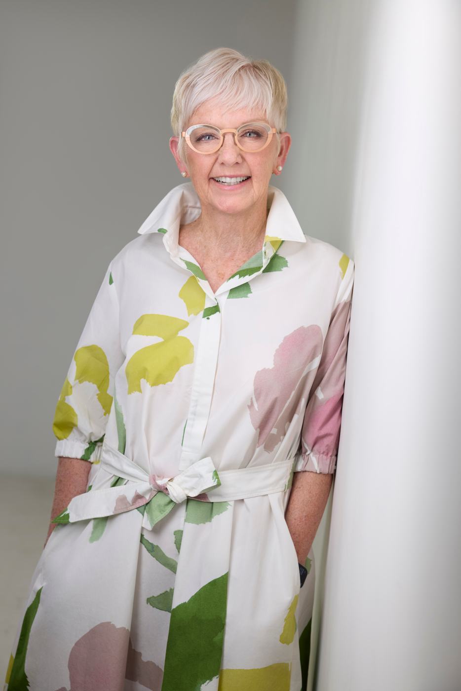 Business portrait in a floral dress against a white wall