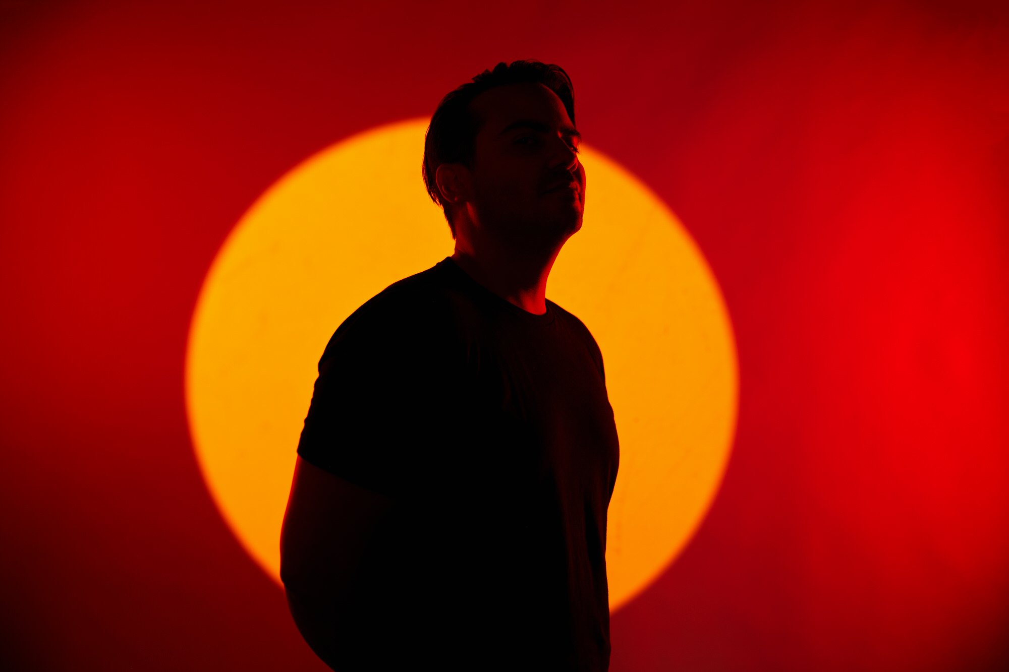 The same session in silhouette against an orange circle of light on red