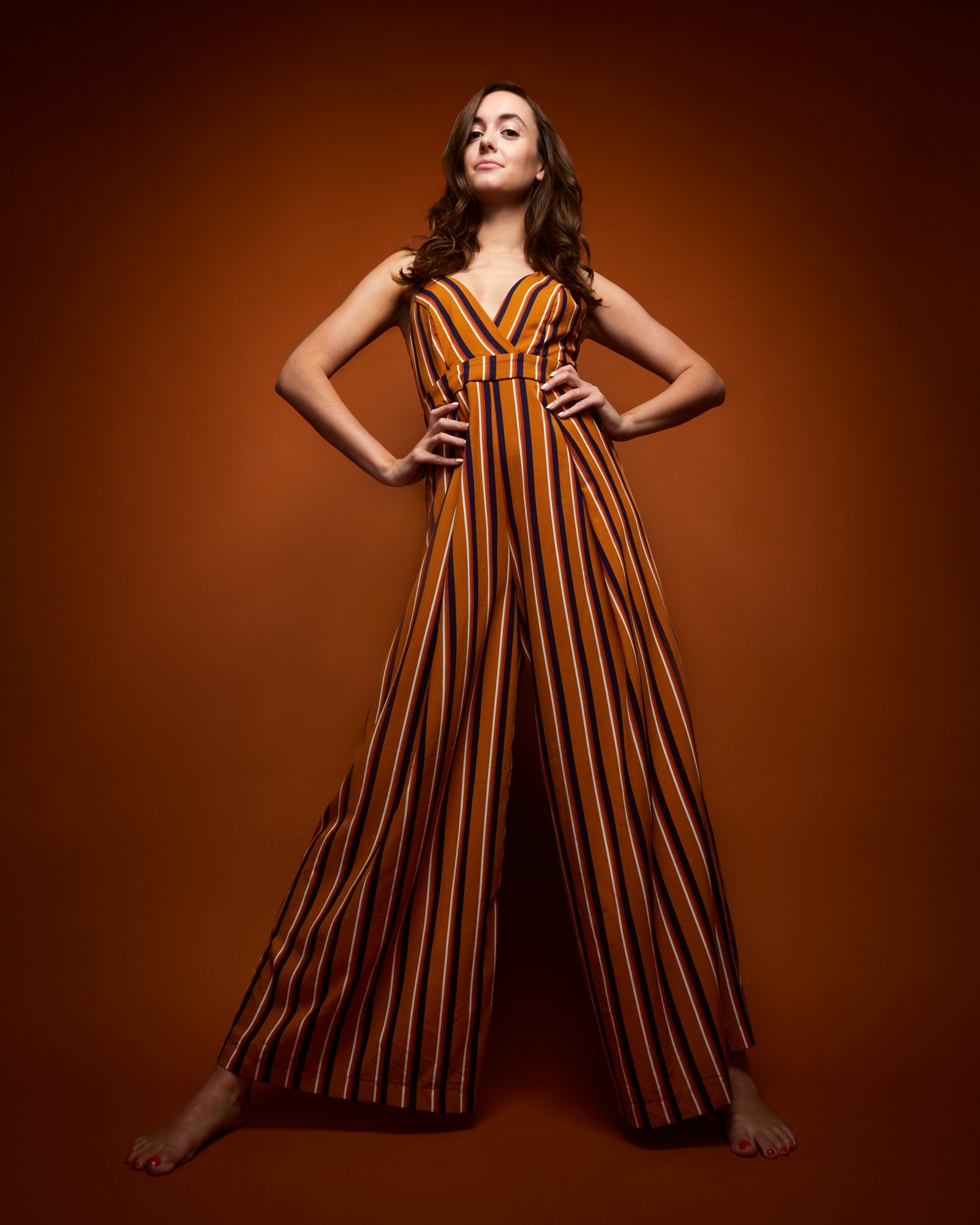 The same session, the striped jumpsuit head to toe against rust