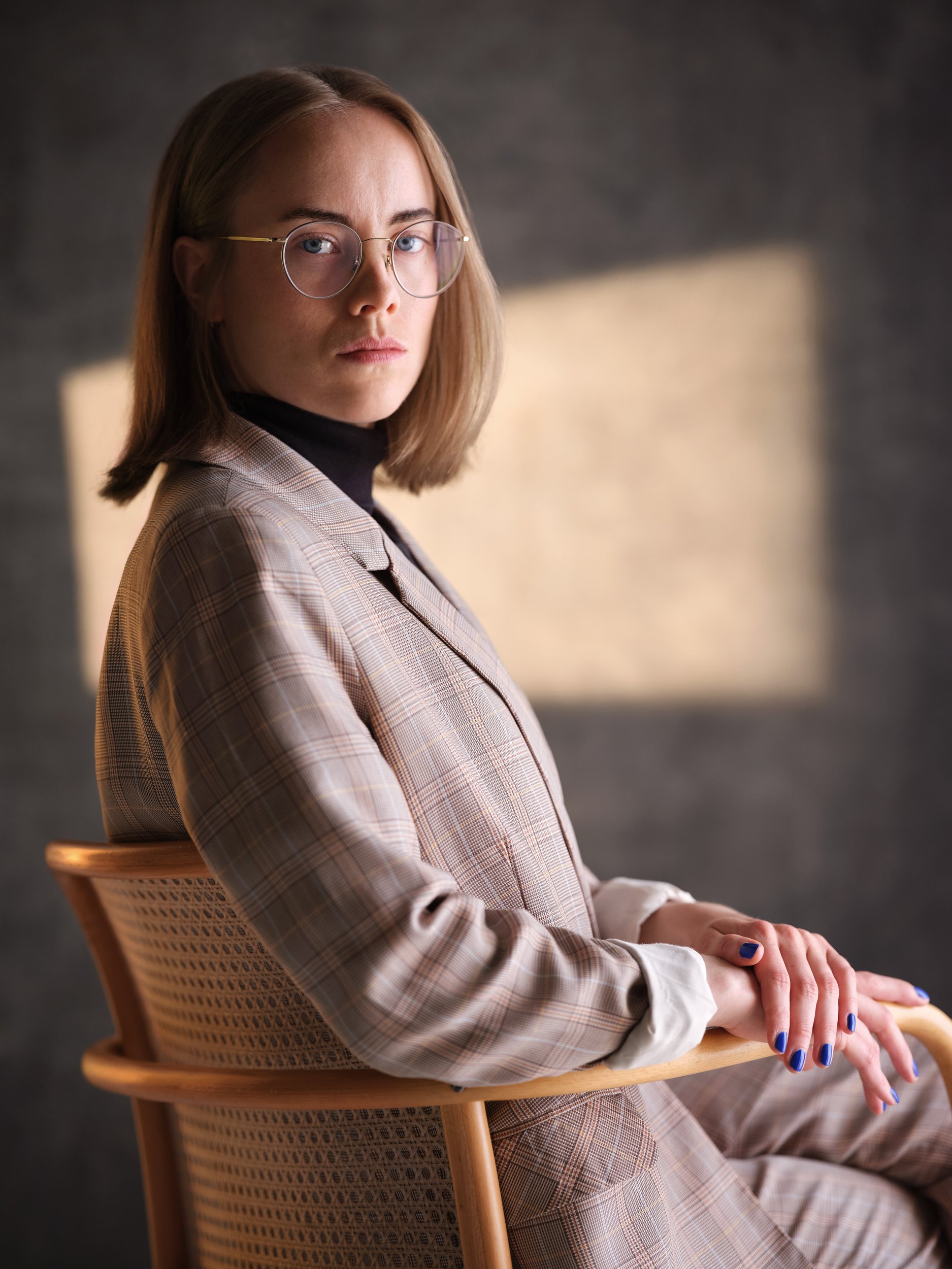 The same session, seated in a cane chair in warm light