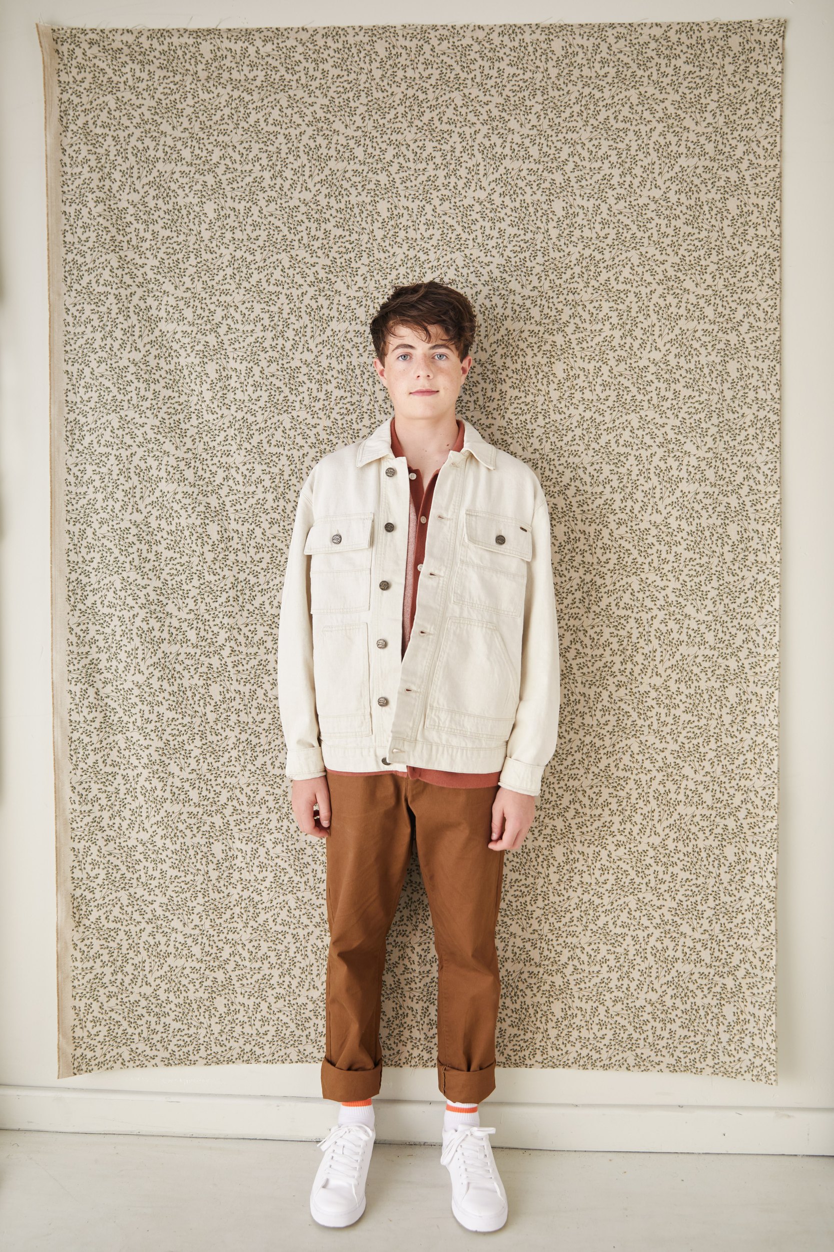 A cream jacket against a floral backdrop, head to toe