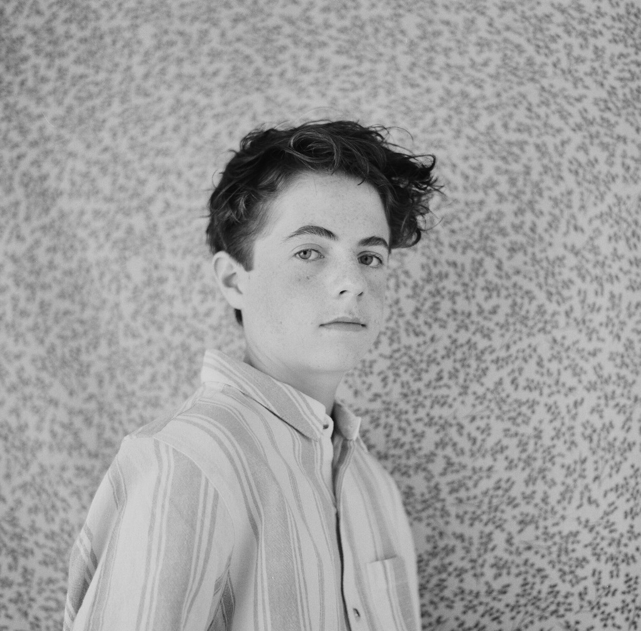 On black-and-white film, a striped shirt against the floral backdrop