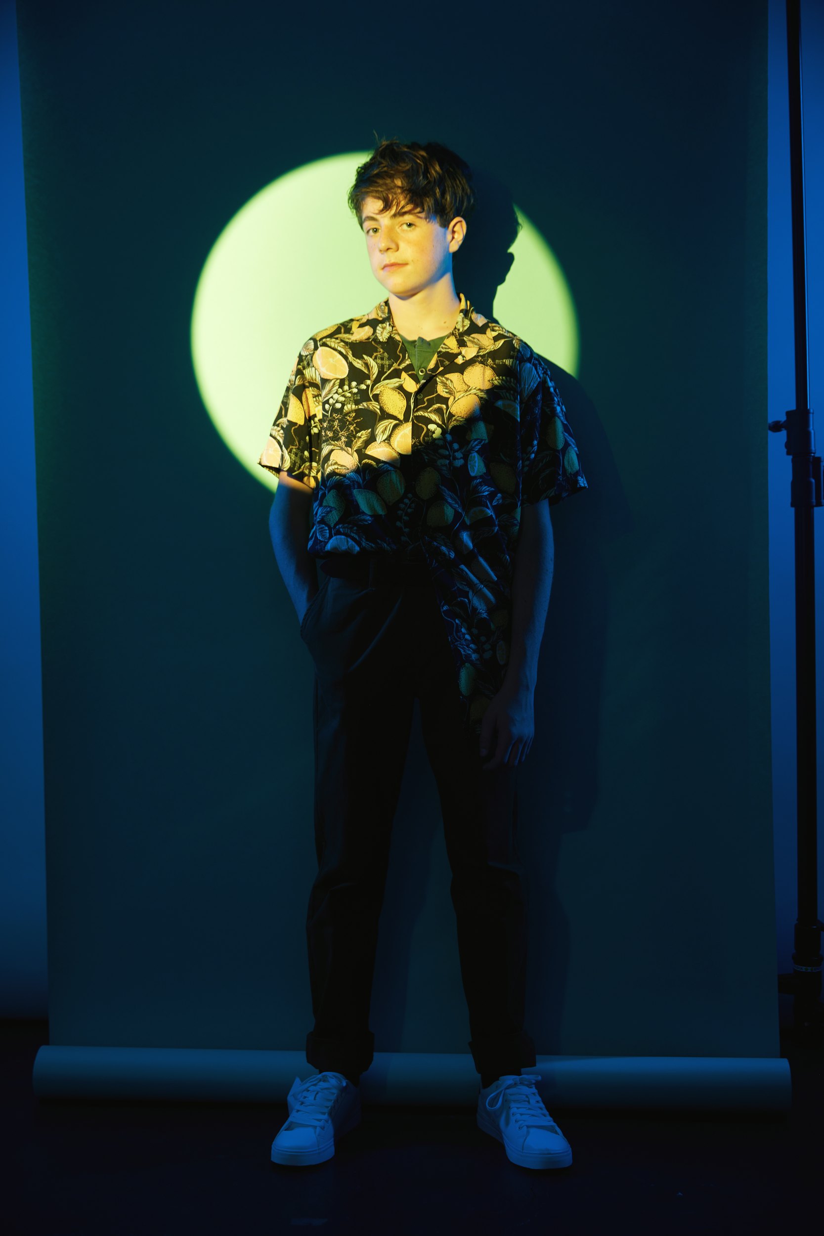 The same session, a floral shirt in a circle of green light on teal, head to toe