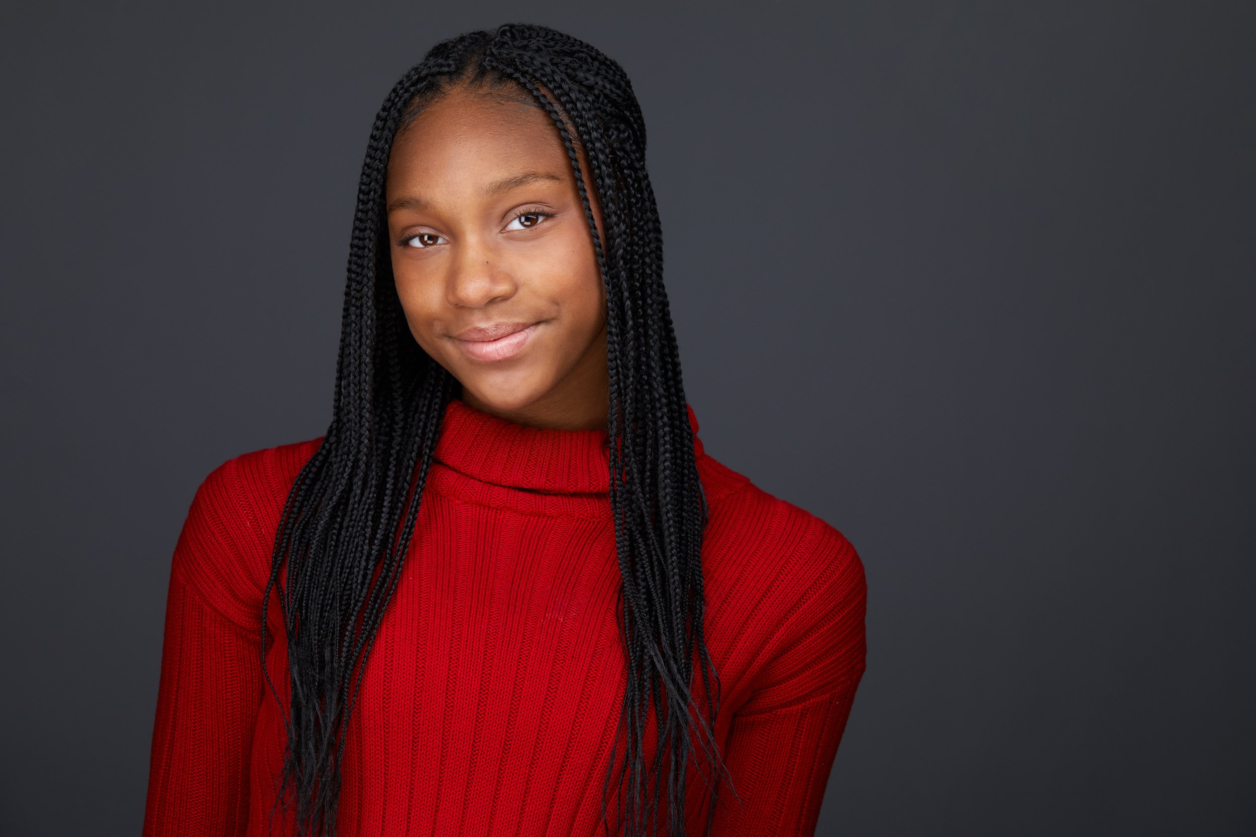 Dance headshot: braids, a red turtleneck against grey