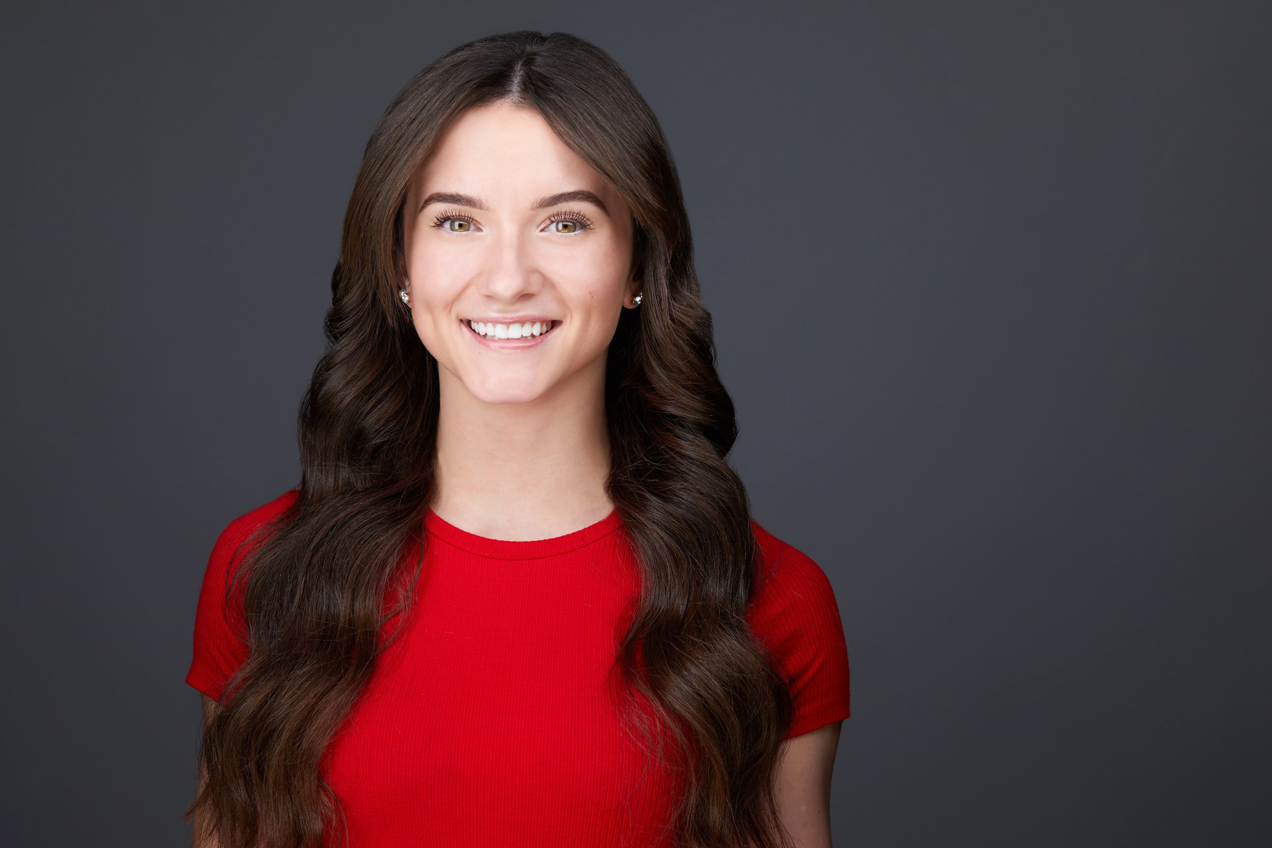 Dance headshot: a red top against grey, smiling