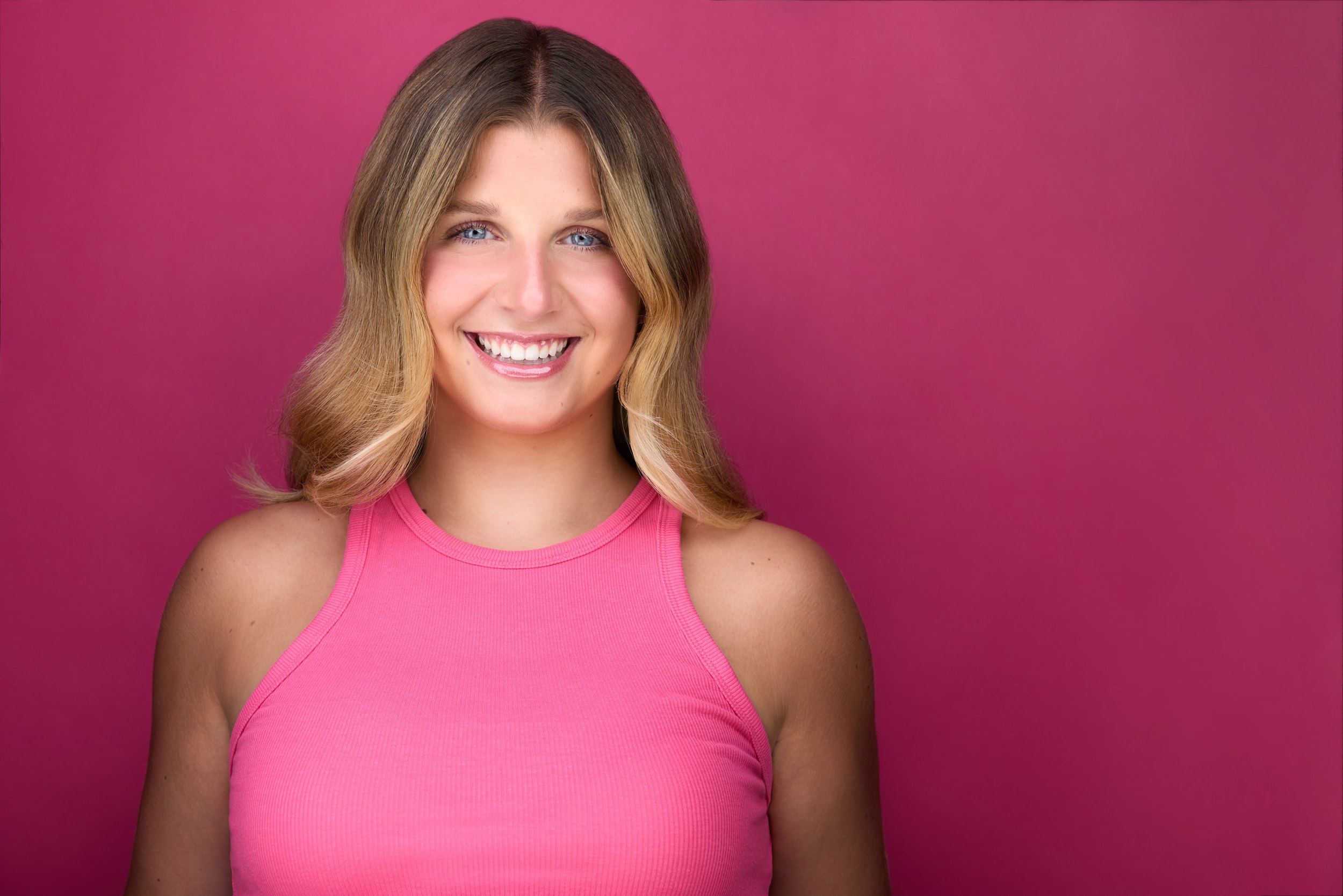 Dance headshot: a pink tank against pink, laughing