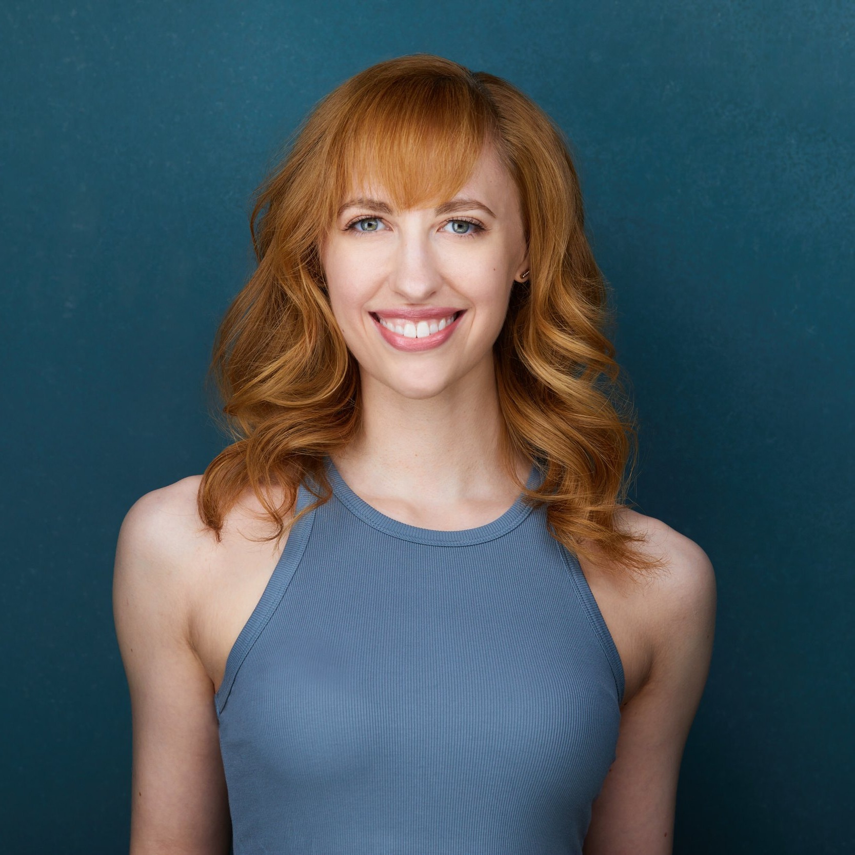 Dance headshot: red hair, a blue-grey top against blue