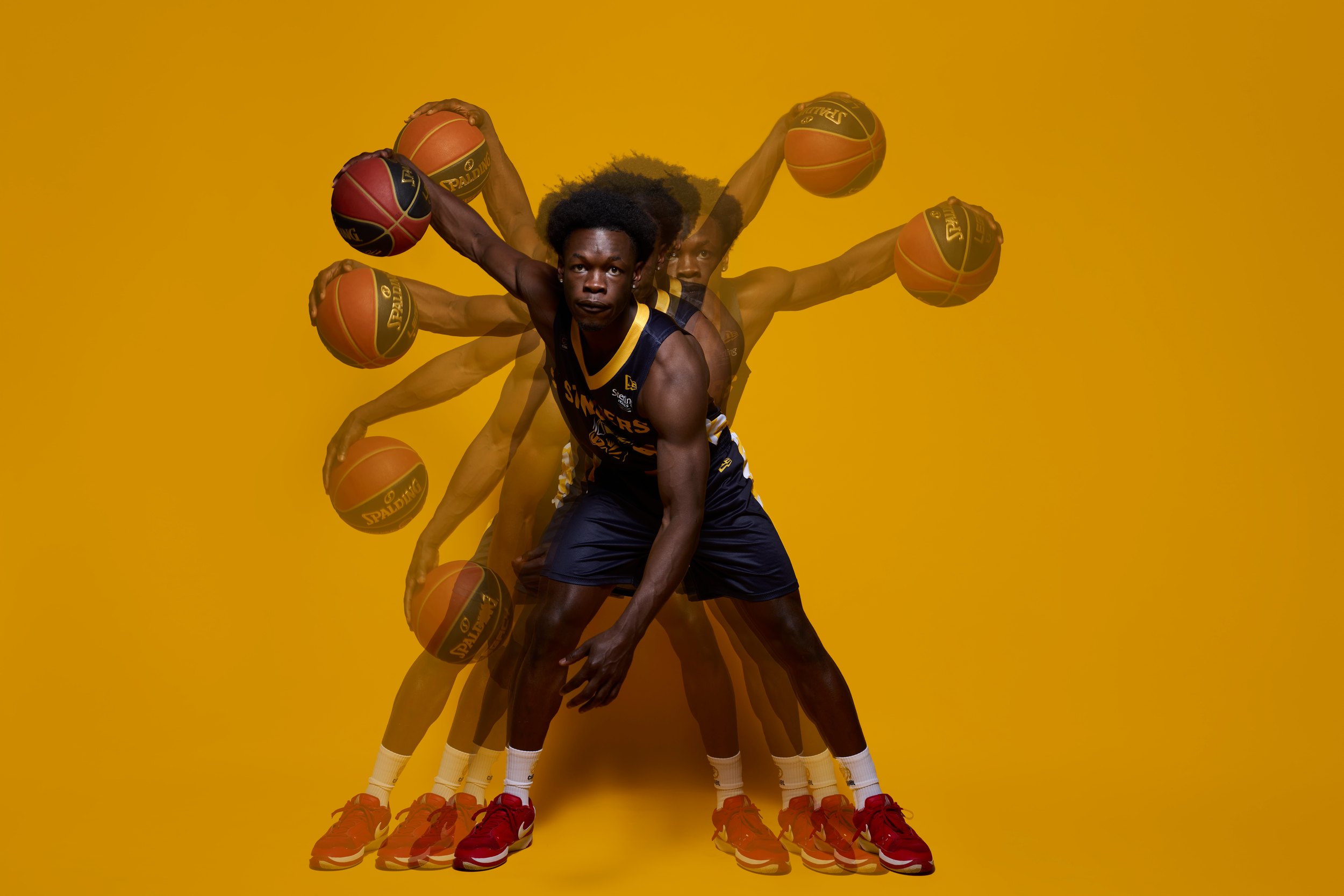 A multiple exposure on the same yellow: the ball and his arms repeated around him as he crouches