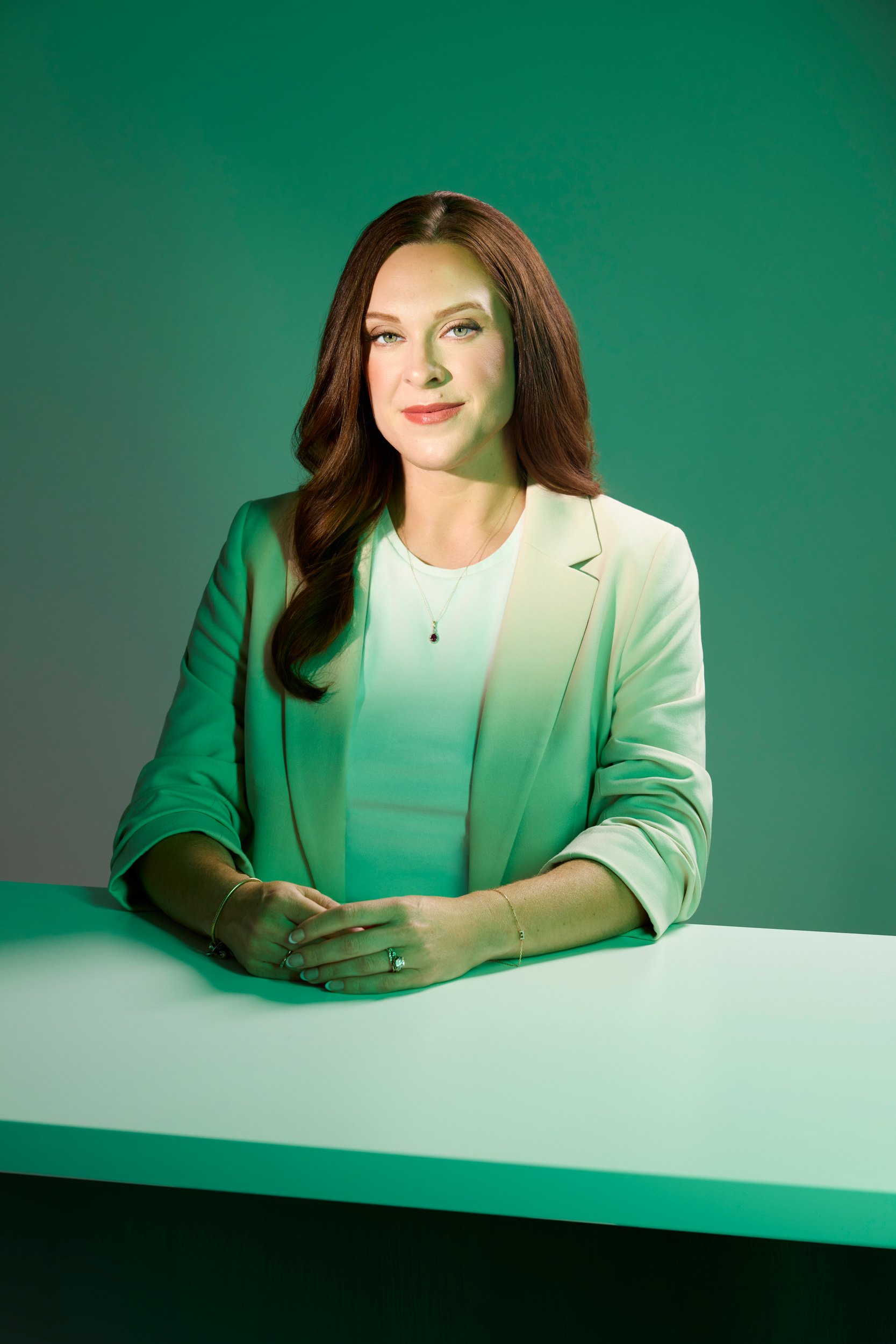 Elise Usunier in a mint jacket, seated at a pale green table