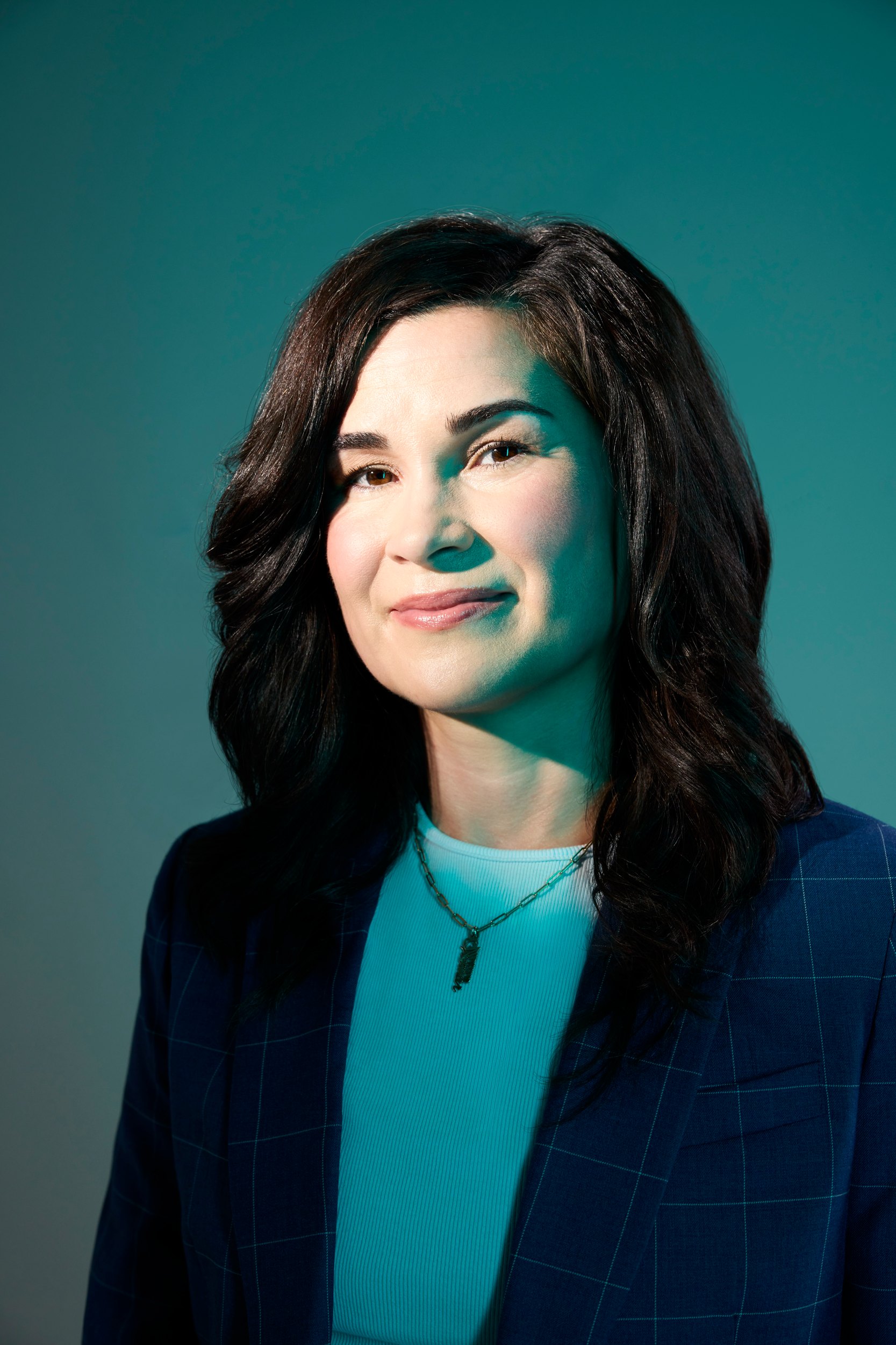 Dr. Blaire Anderson, turned, against the same teal