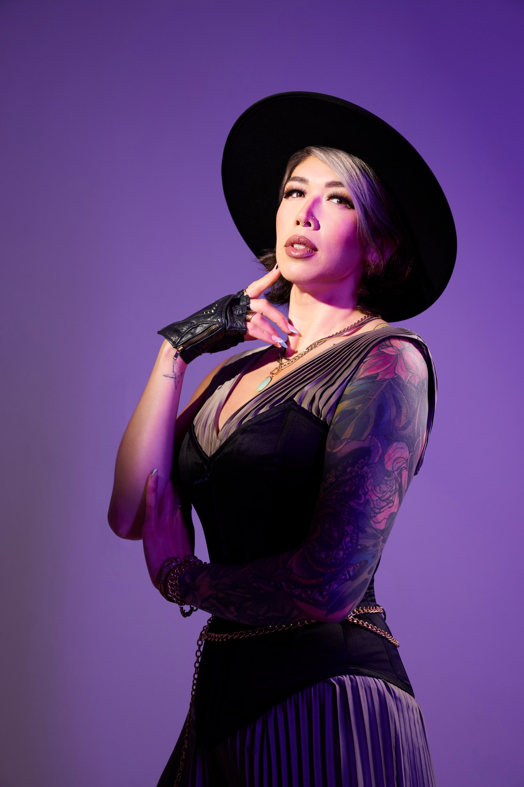 Jade Connors in a wide-brimmed hat and black lace against violet