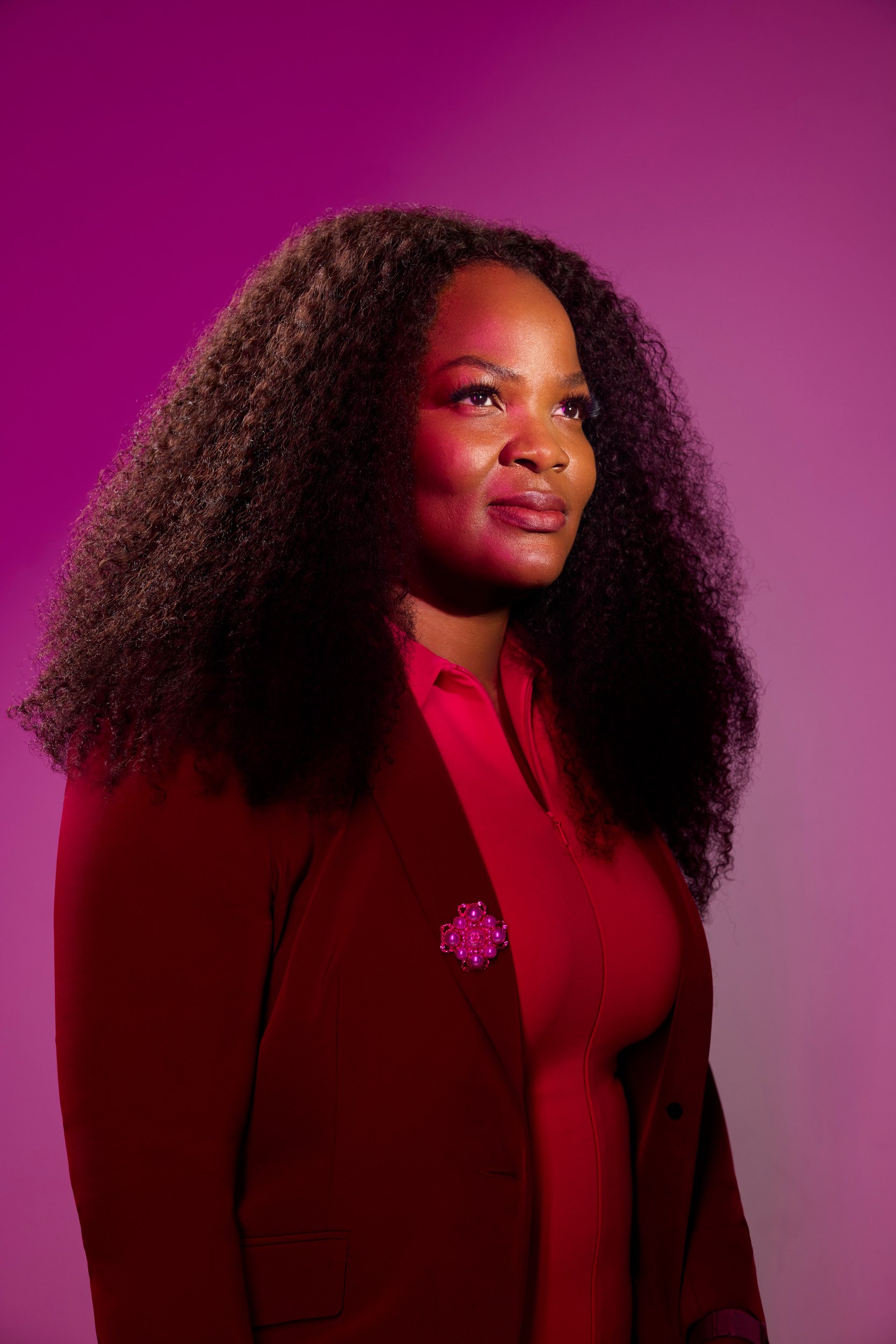 Tracy F. Barry in red against magenta, looking off frame
