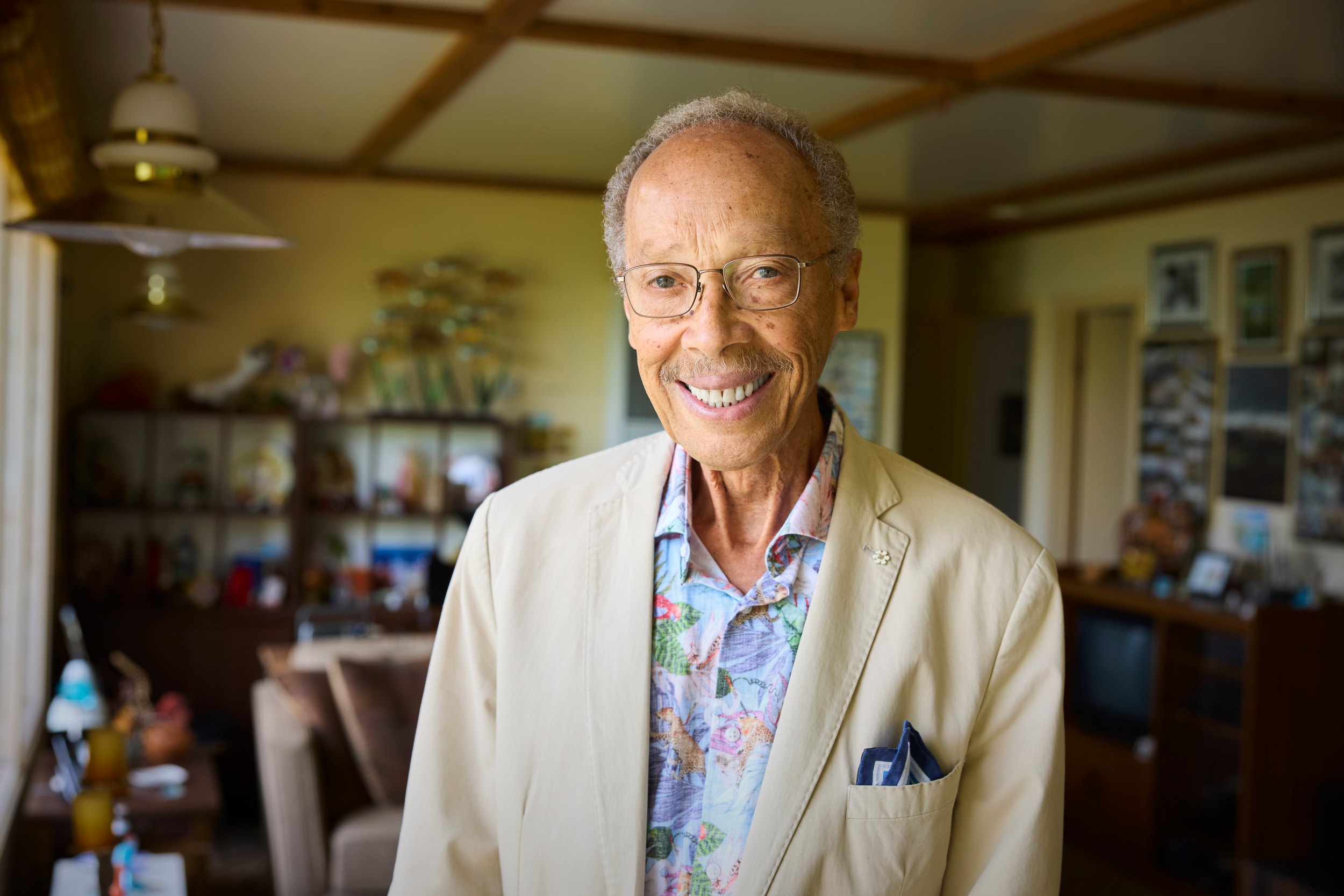 Dr. Anthony Fields at home in a cream jacket and a patterned shirt, the room behind him