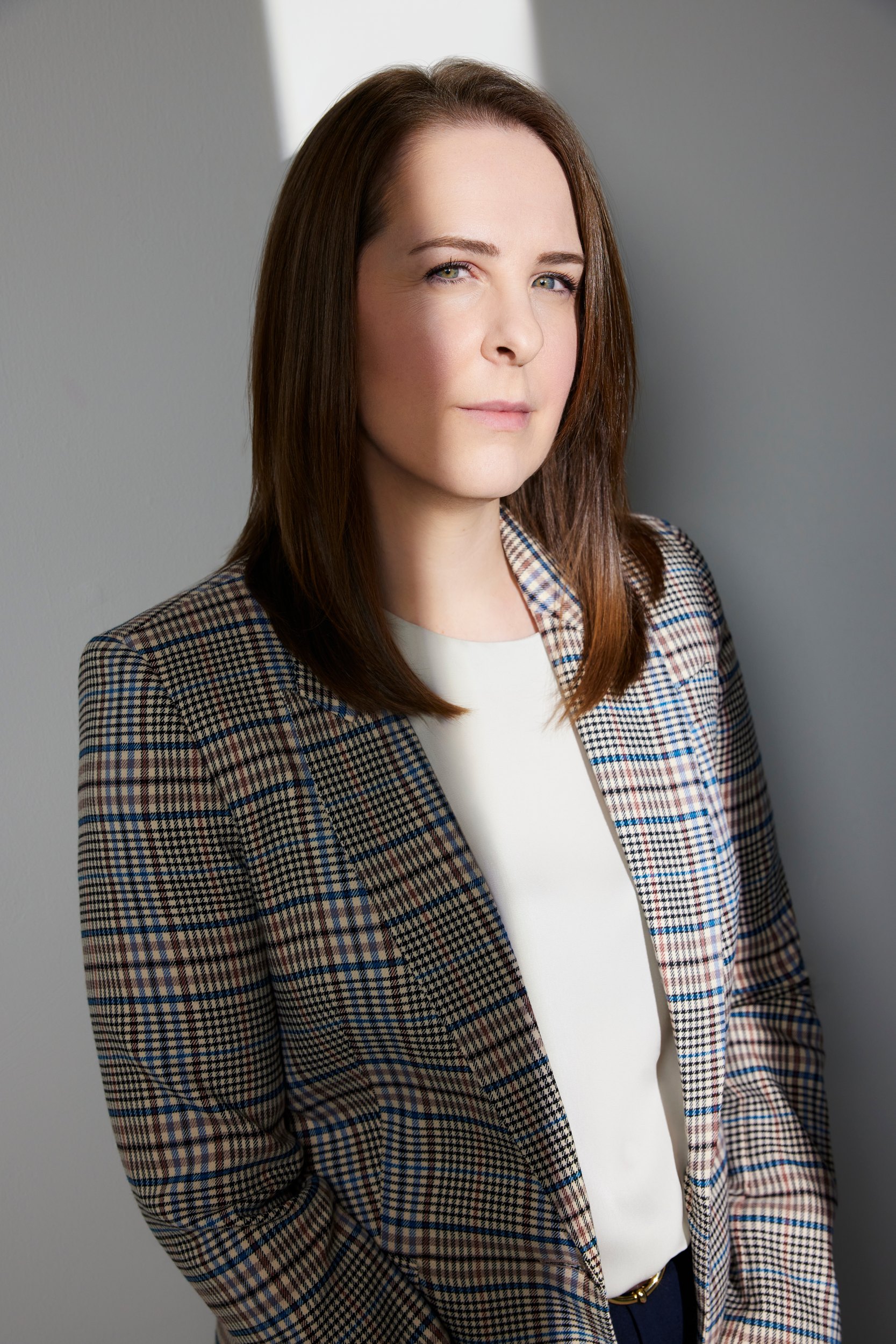 A plain portrait against grey, the checked blazer over a cream top
