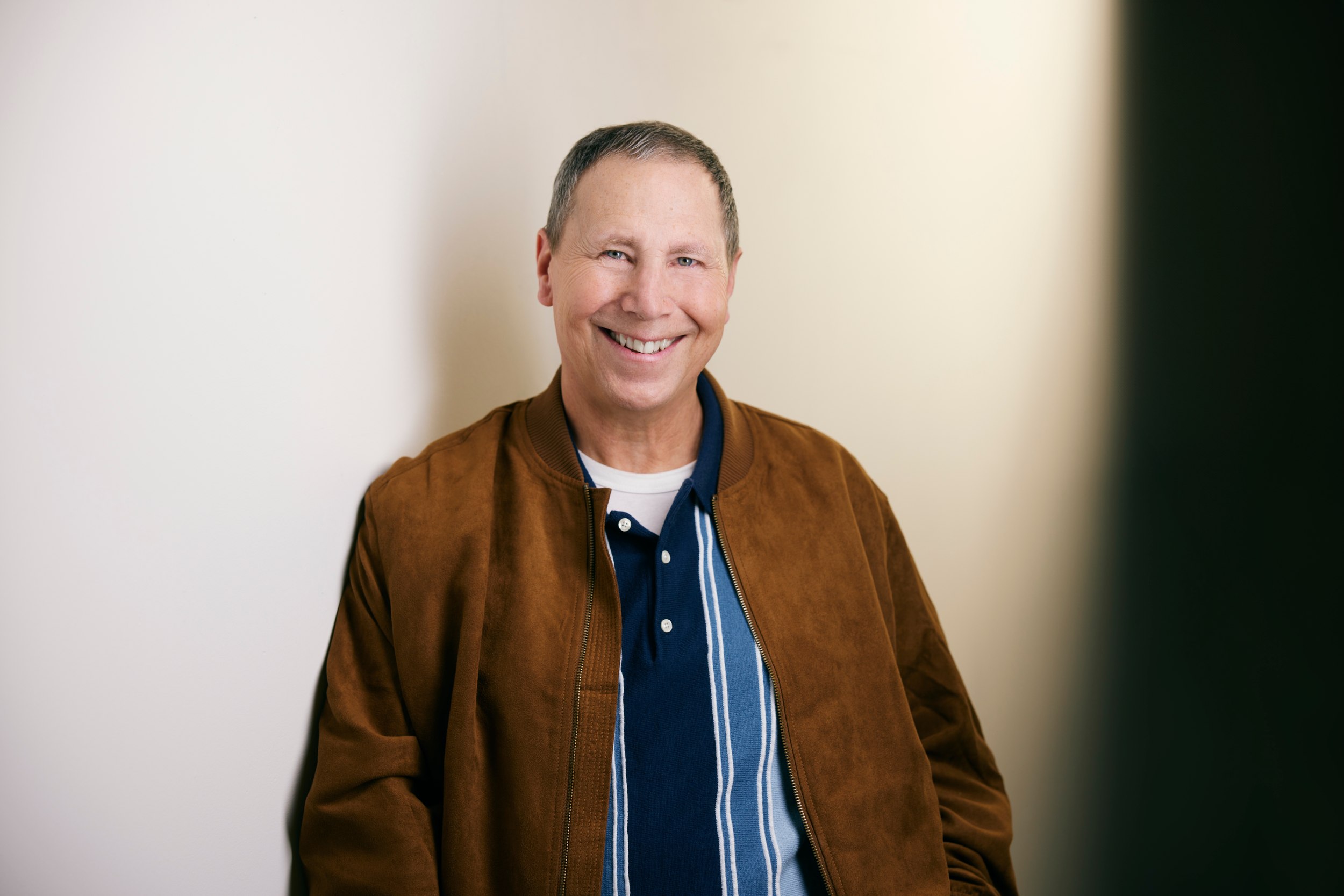 Laughing, the jacket open over a striped shirt